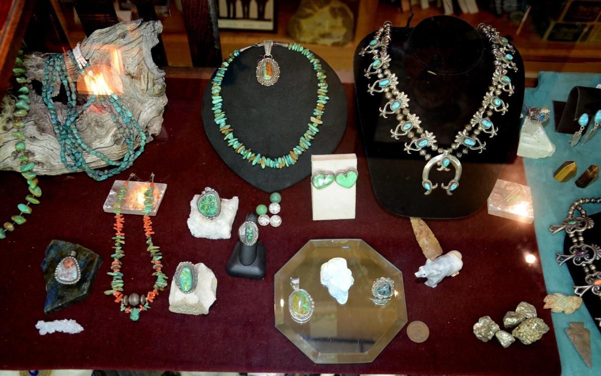 Jewelry display with turquoise and gemstone necklaces, rings, and earrings on black velvet.