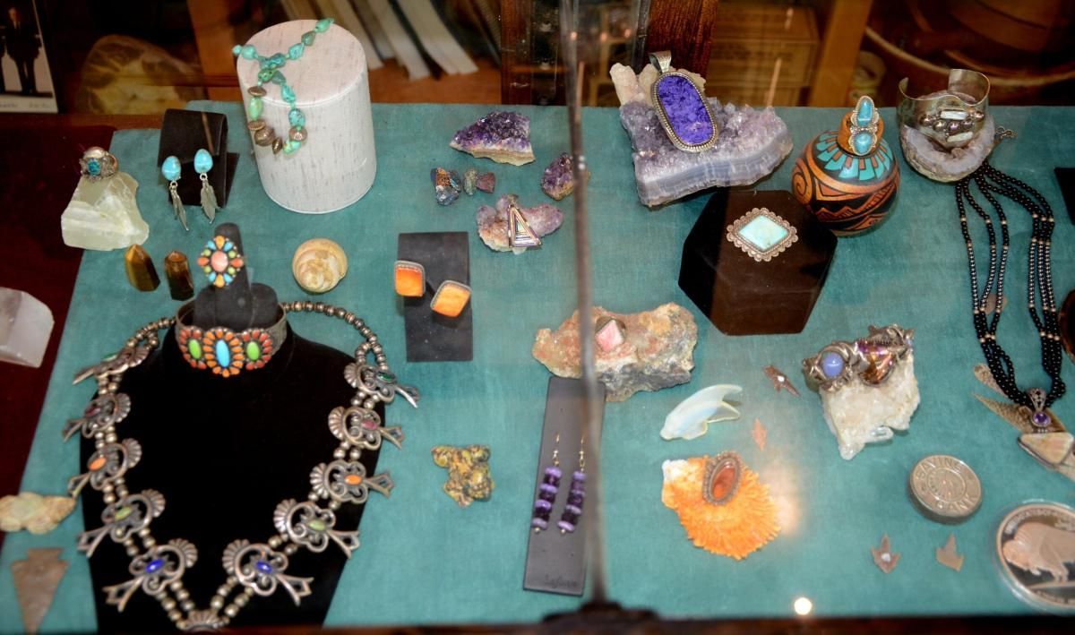 Jewelry display: necklaces, earrings, rings, and gemstones on a teal surface.