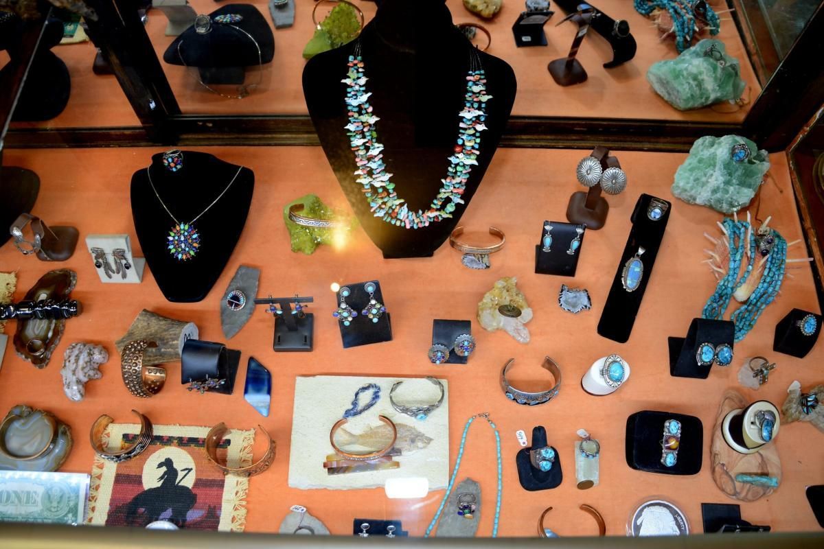 Jewelry display case with turquoise necklaces, bracelets, rings, and earrings. Orange backdrop.