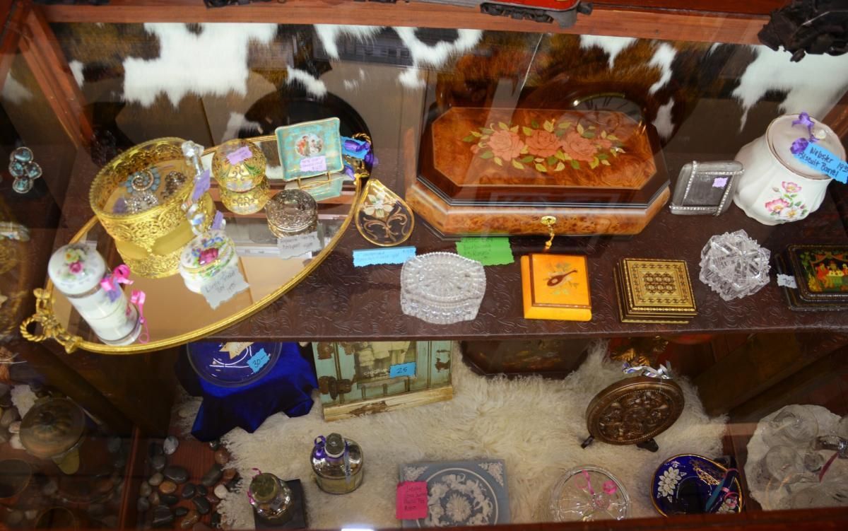 A display case filled with decorative jewelry boxes and trinkets, some gold-toned, others crystal.