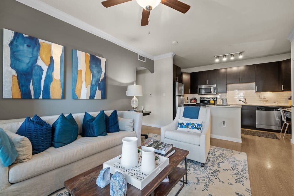 A living room with a couch, chair, coffee table, and ceiling fan at Marquis at the Reserve in Katy, TX.