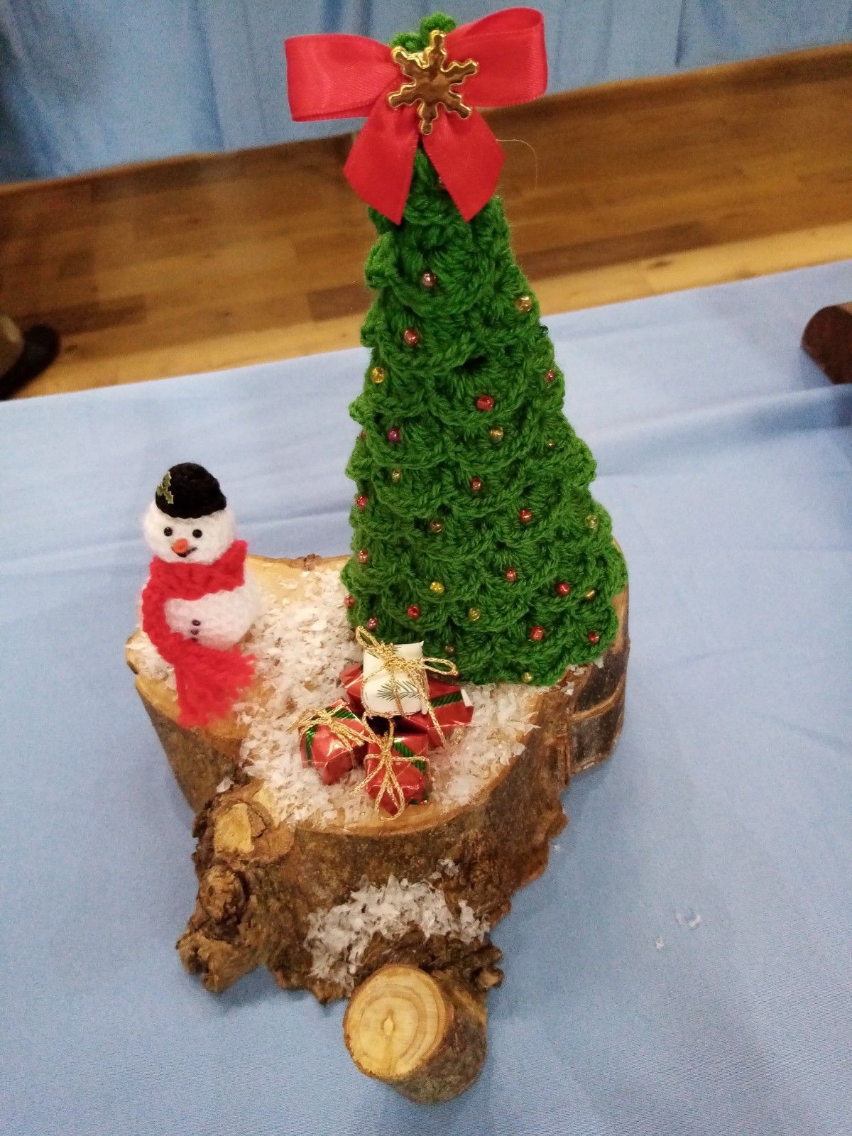 A crocheted christmas tree with a red bow and a snowman
