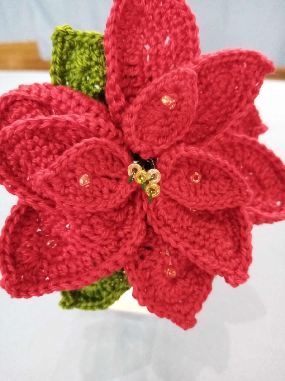 A close up of a crocheted poinsettia flower