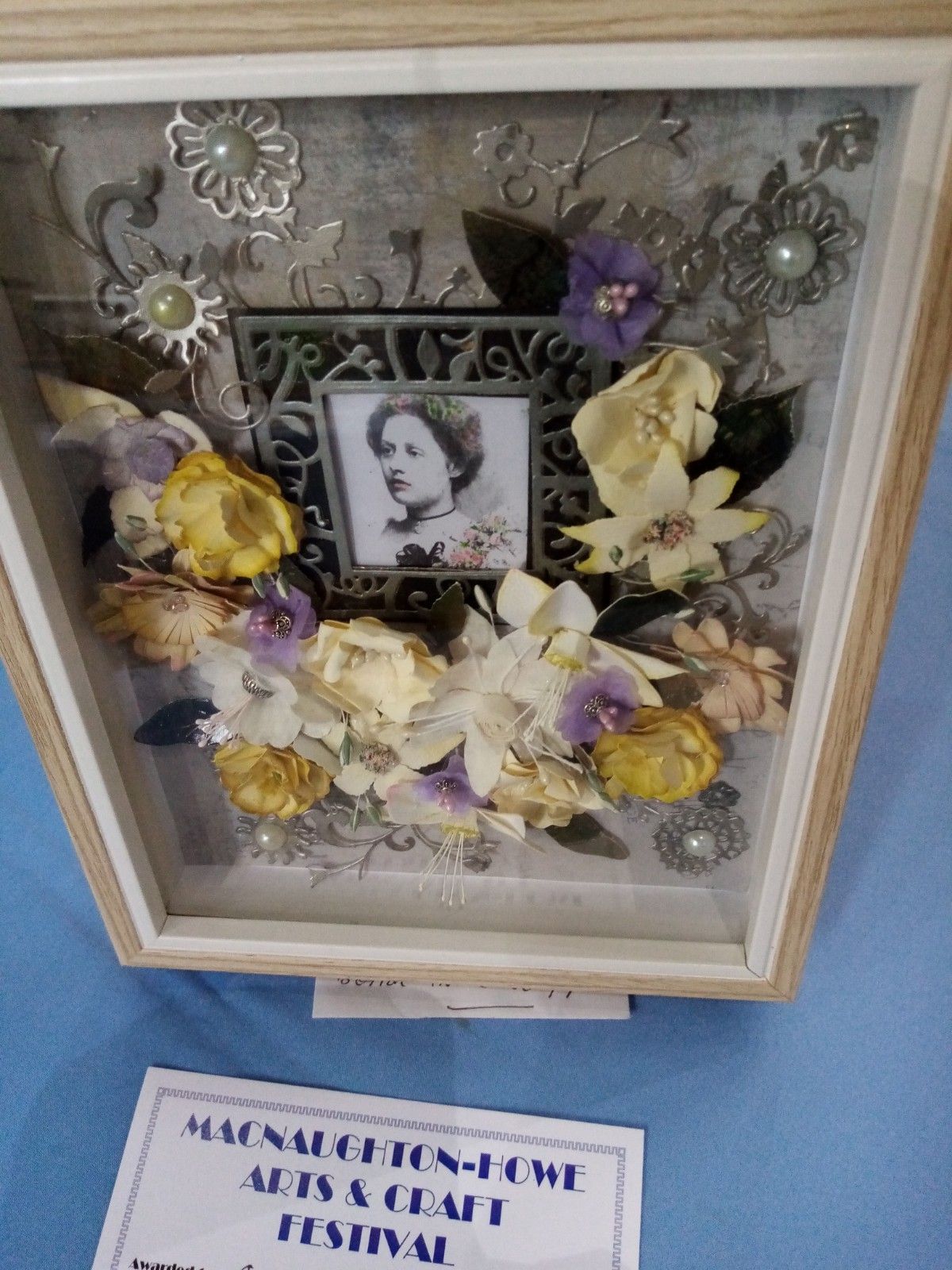 A picture frame with flowers and a picture of a woman in it