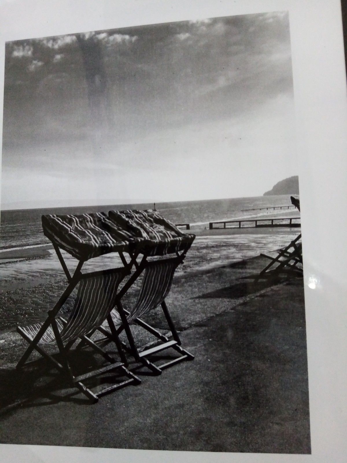 A black and white photo of folding chairs on a beach