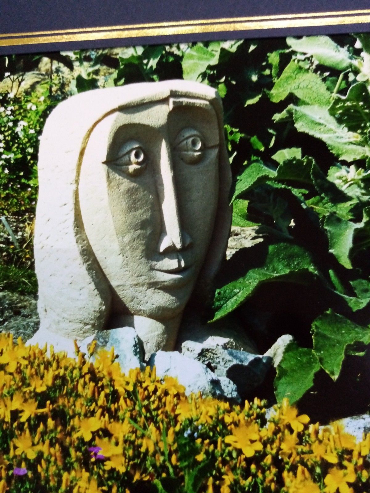 A statue of a woman 's face is surrounded by yellow flowers