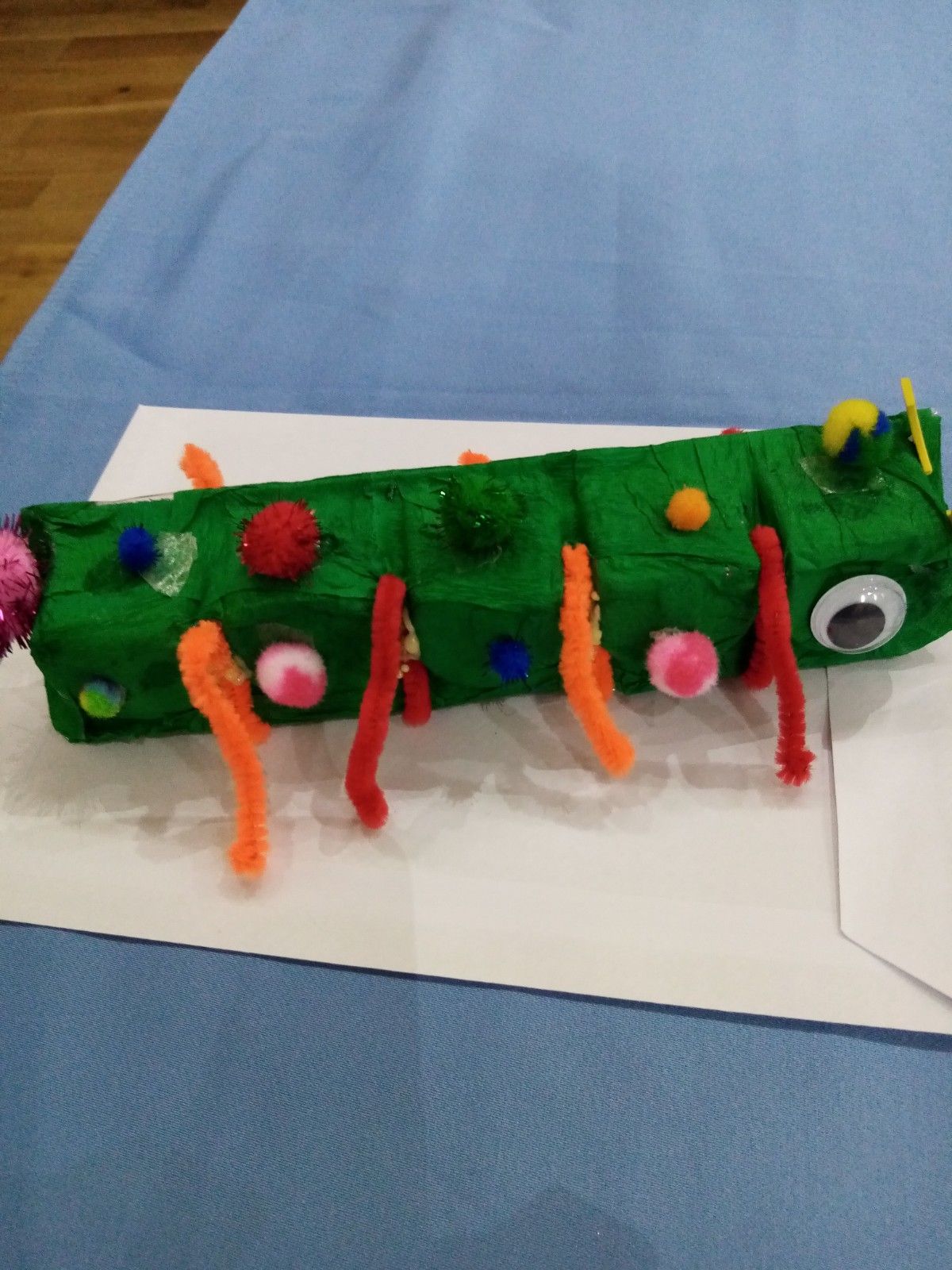 A green caterpillar made out of cardboard boxes and pipe cleaners