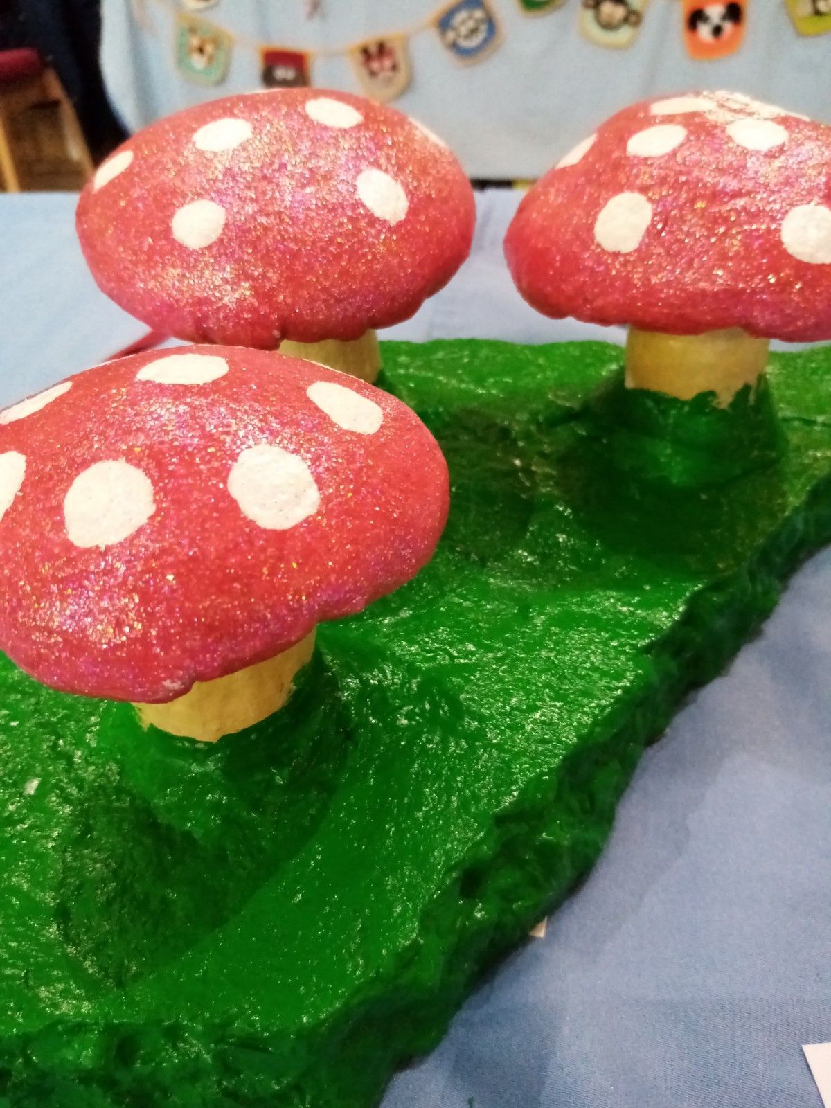 Three red mushrooms with white polka dots are sitting on a green surface