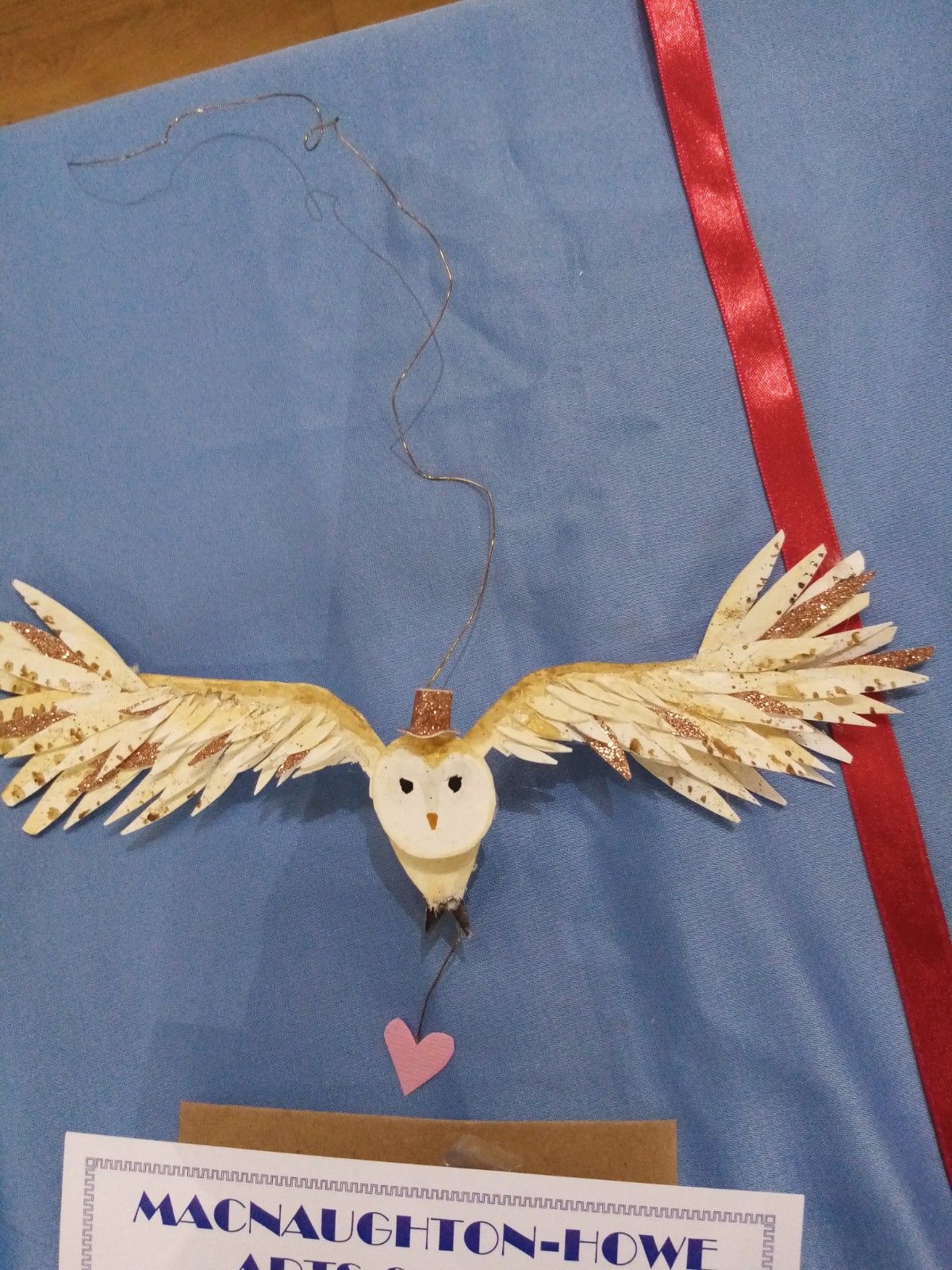 An owl made out of feathers is on a blue cloth