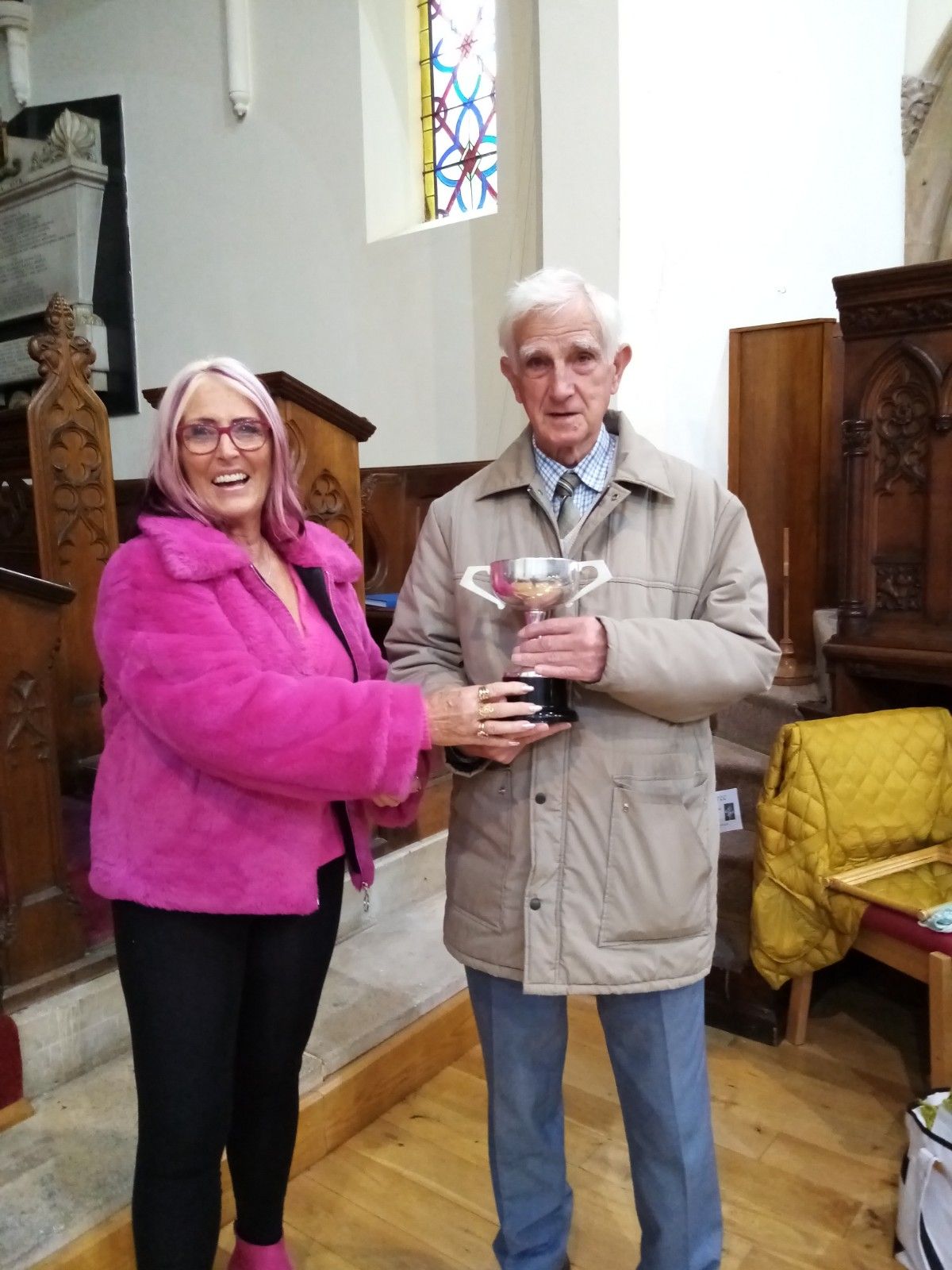 A man and a woman are holding a trophy in a church.