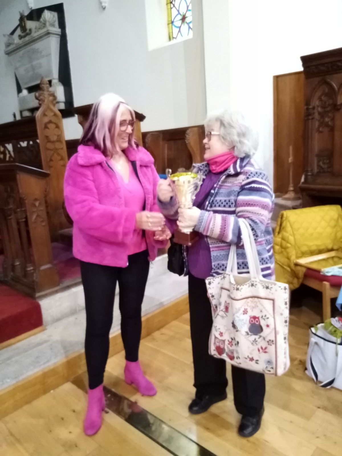 Two women are standing in a church talking to each other
