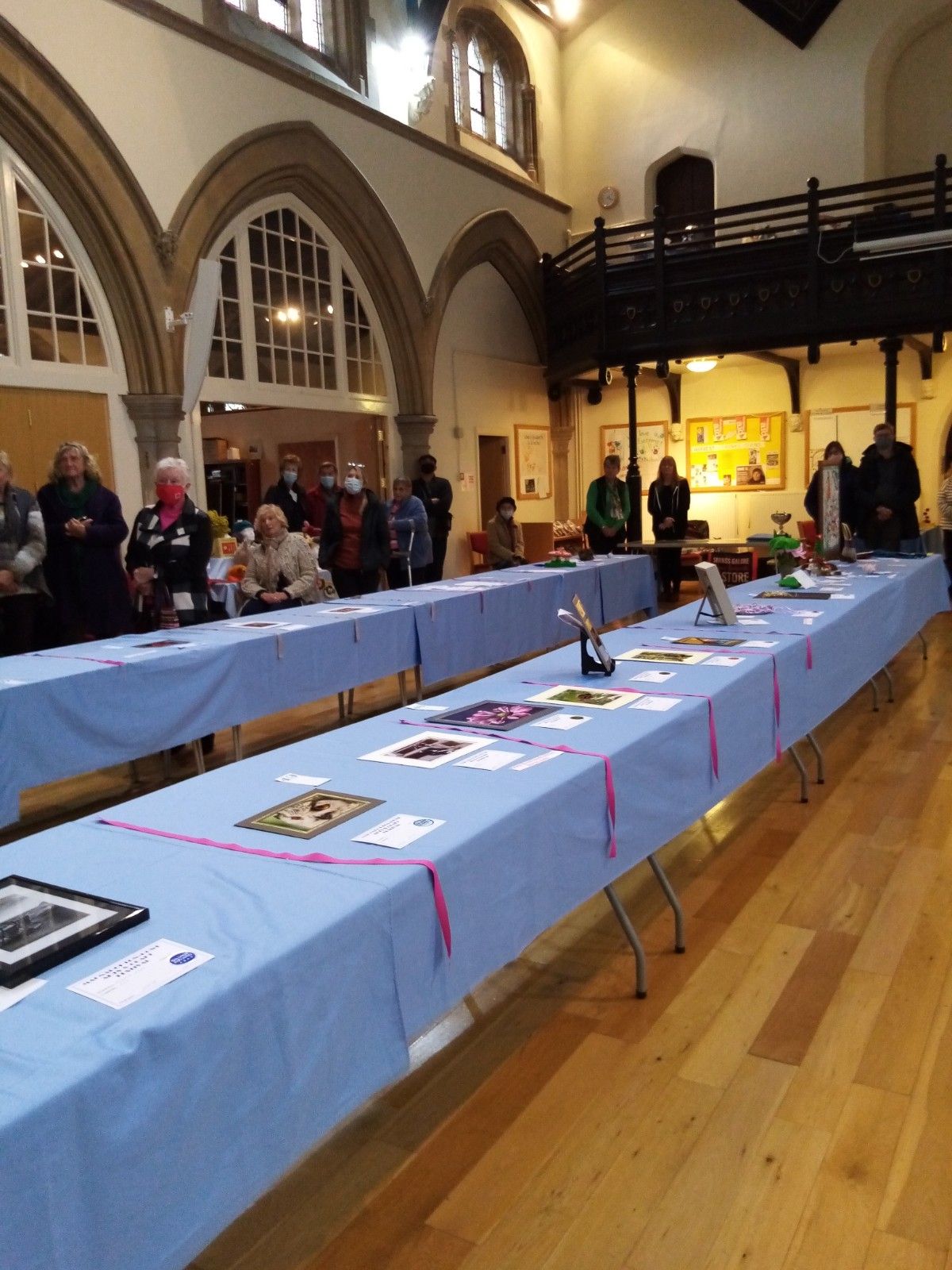 A group of people are standing around long tables in a room.