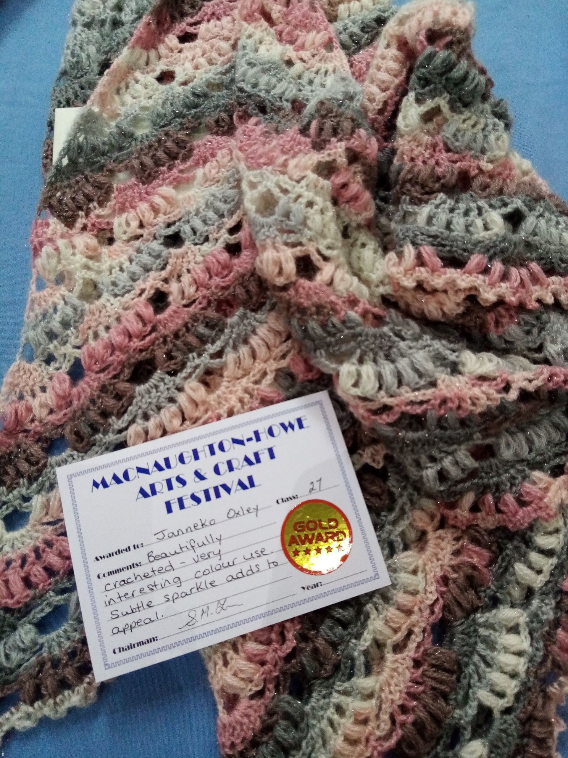 A crocheted scarf with a certificate on top of it