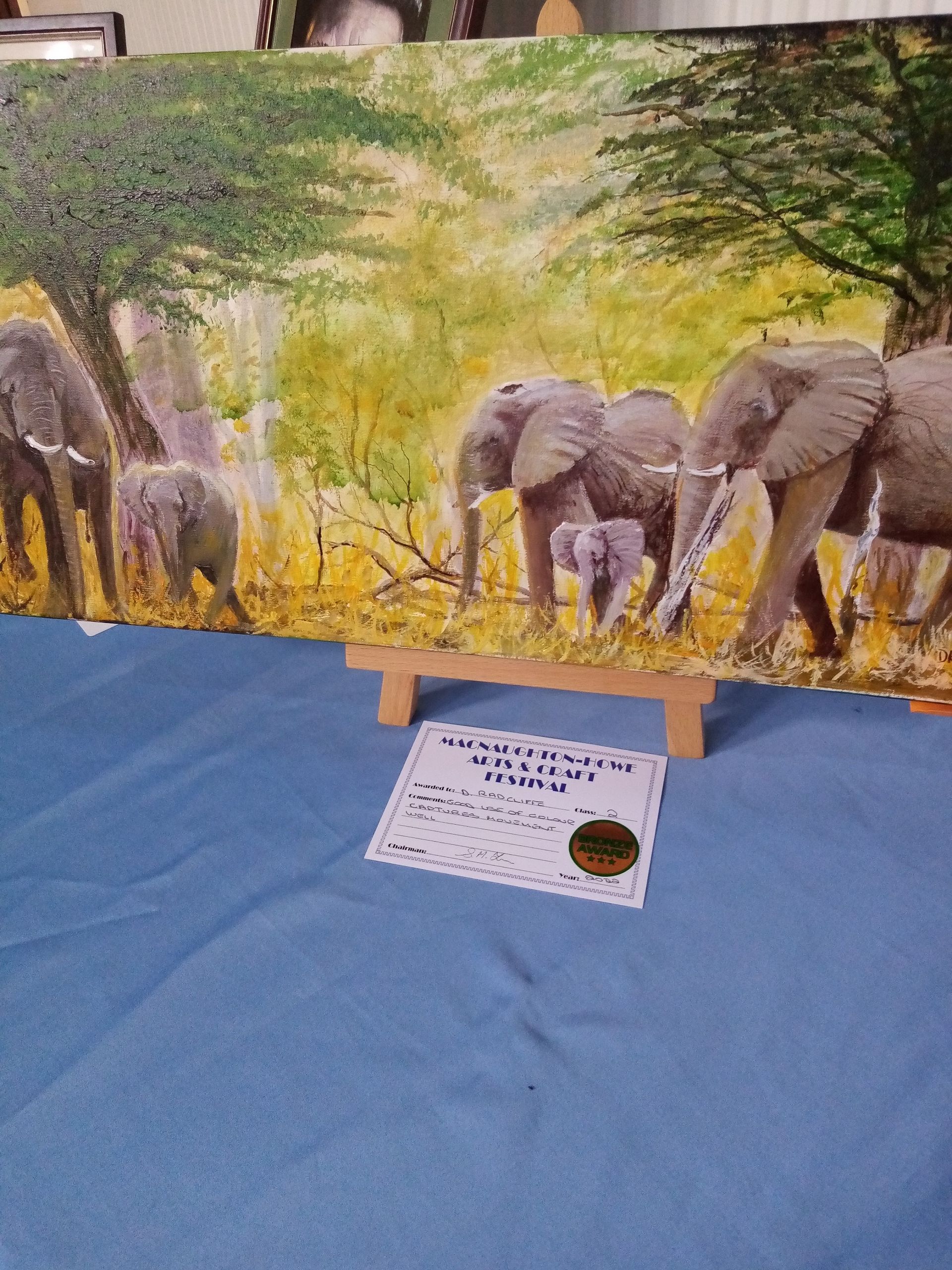 A painting of elephants is sitting on a table next to a certificate.
