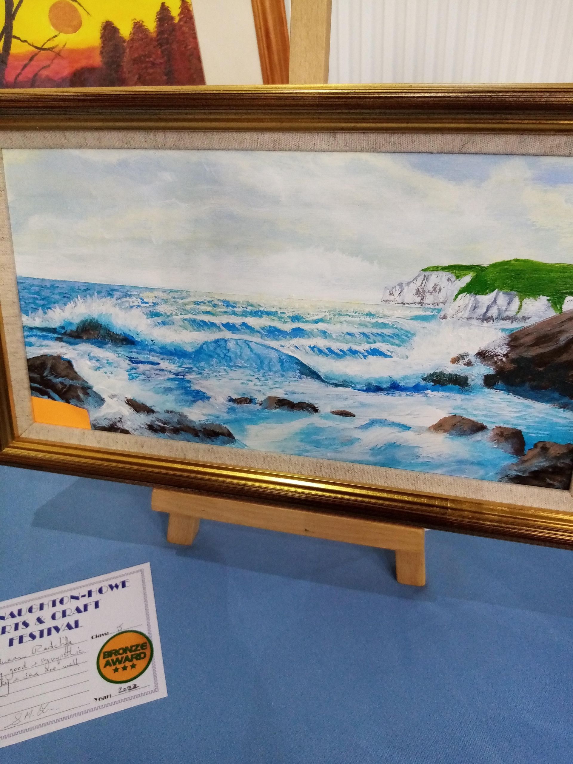 A framed painting of waves crashing on a rocky beach