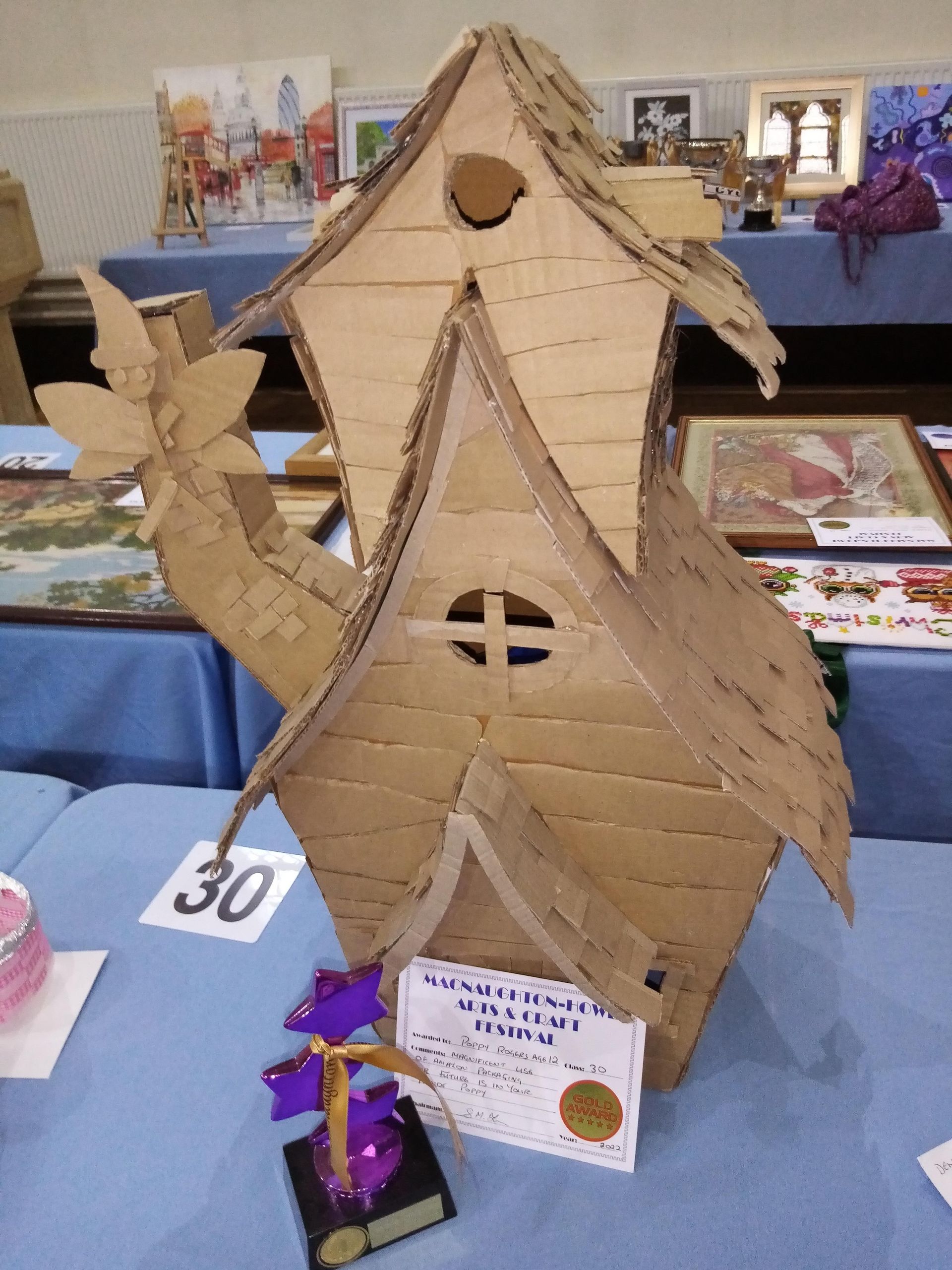 A cardboard birdhouse is sitting on a table with the number 30 on it