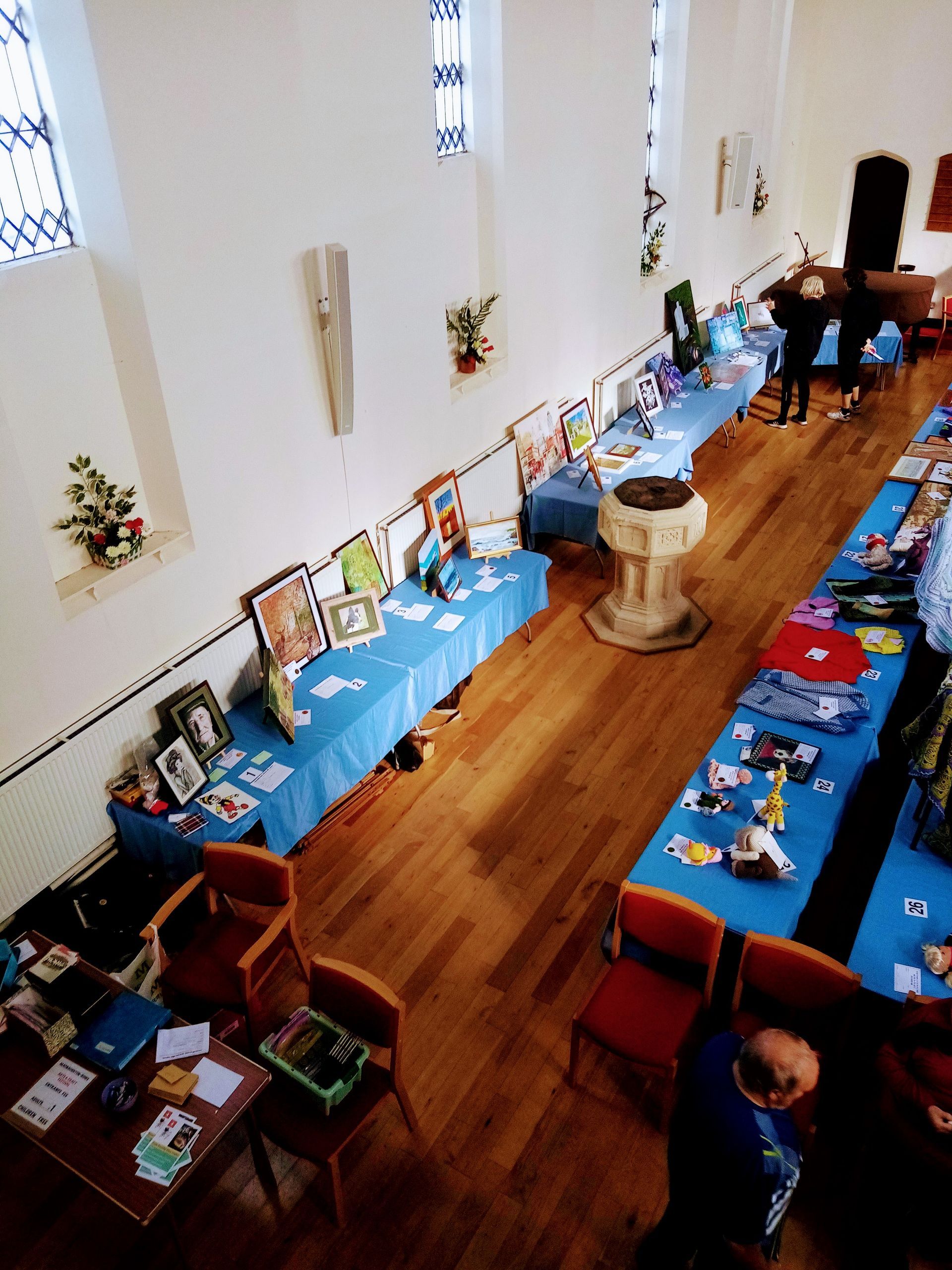 An aerial view of a room with tables and chairs and a baptismal font