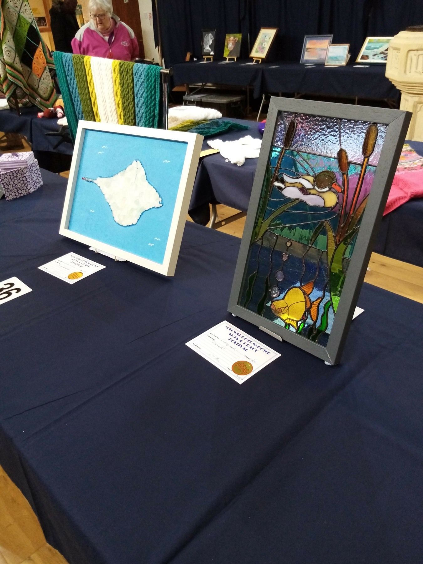 Two paintings on a table with a blue table cloth
