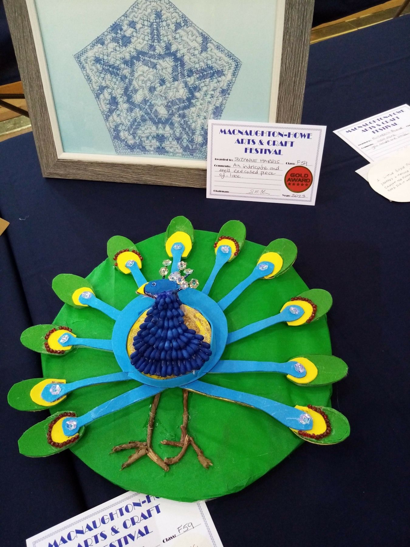 A peacock made out of a cd sits on a table