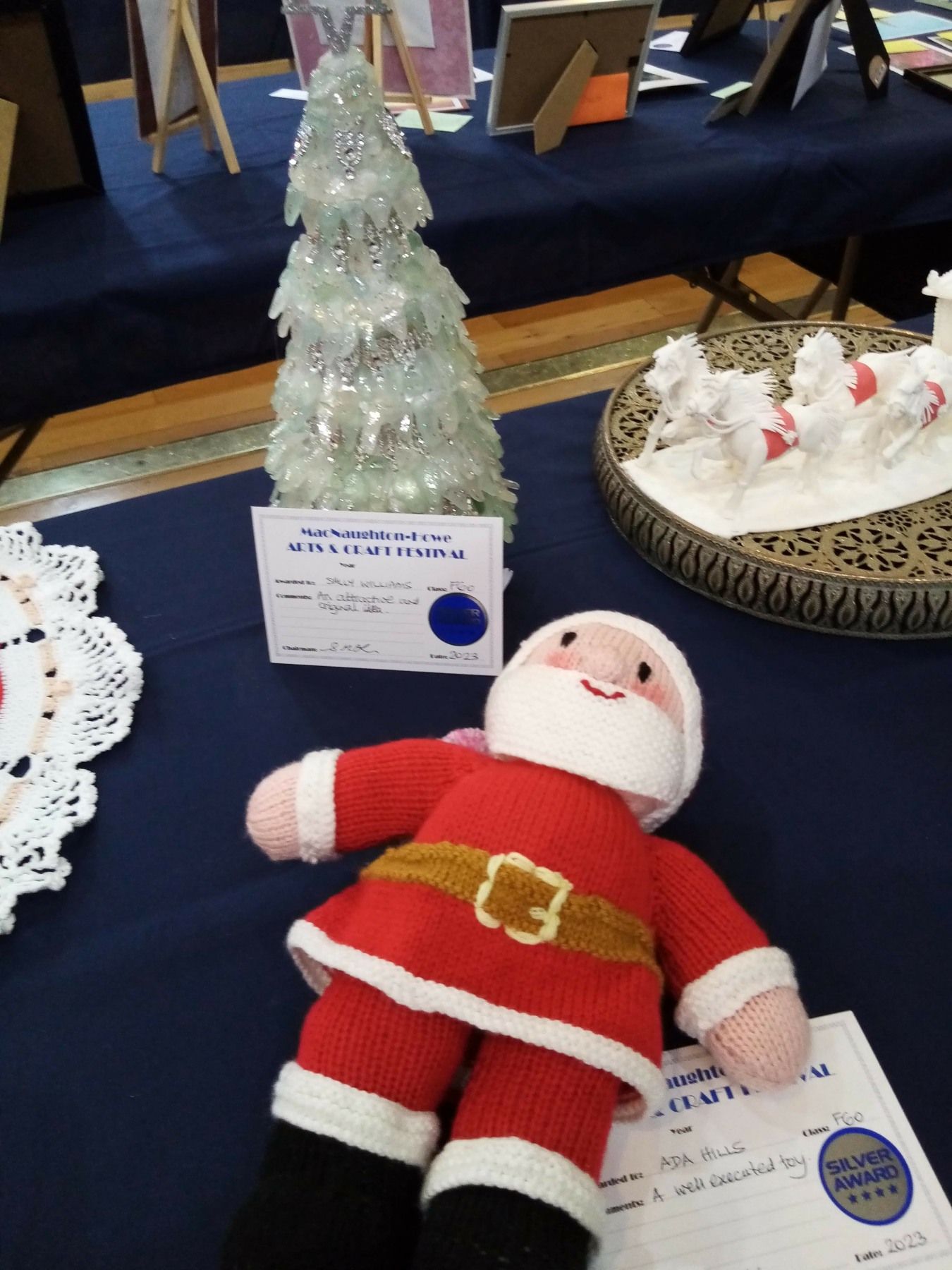 A stuffed santa is on a table next to a christmas tree