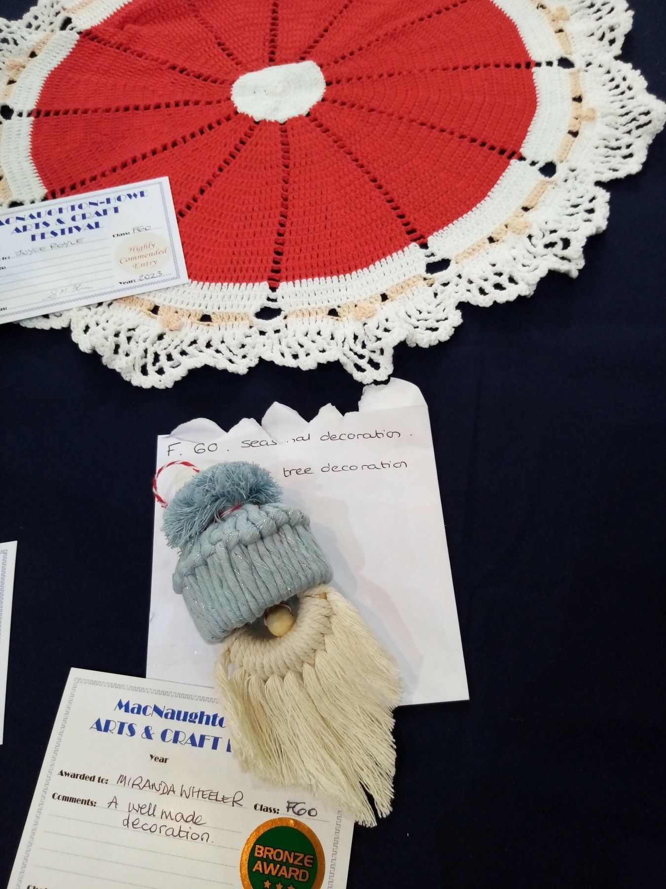 A red and white crocheted christmas tree skirt is on a table