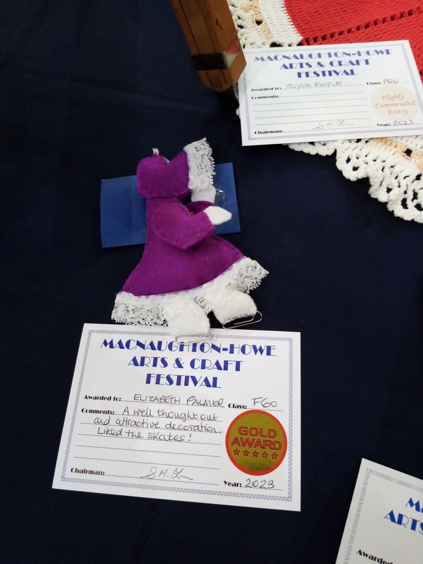 A purple stuffed animal sits on a table next to a certificate that says ' wool award ' on it