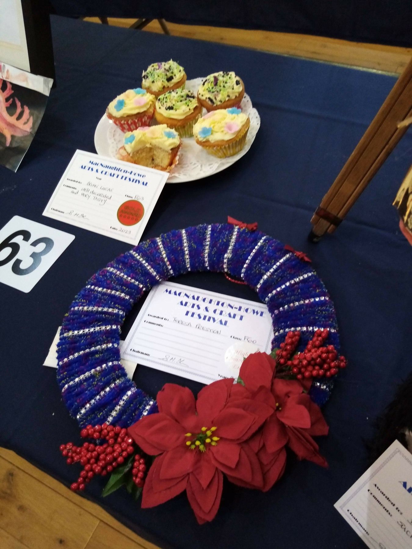 A table with a wreath and a plate of cupcakes on it