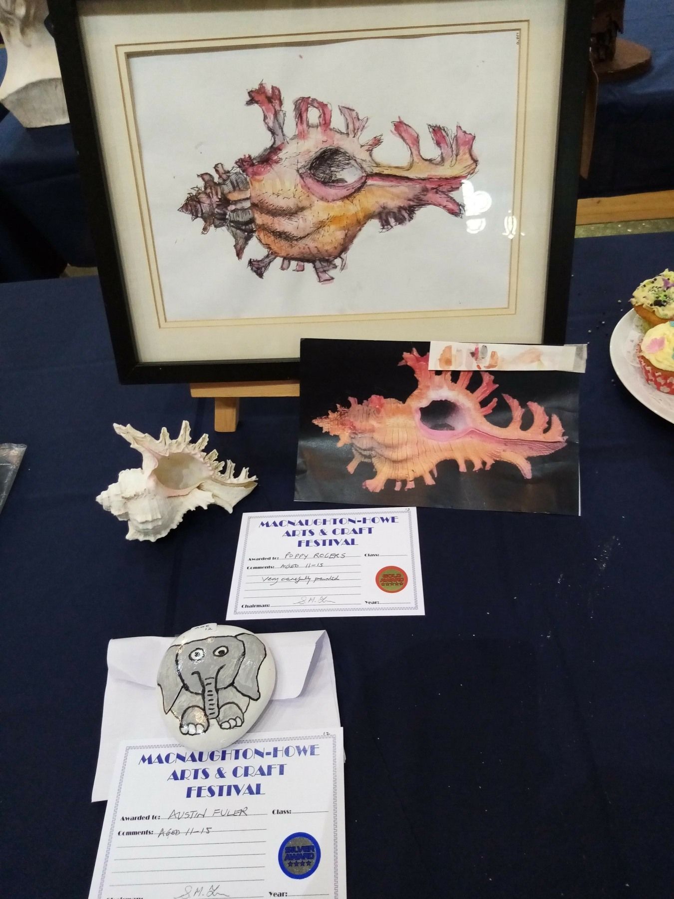 A painting of a sea shell is on a table next to a certificate