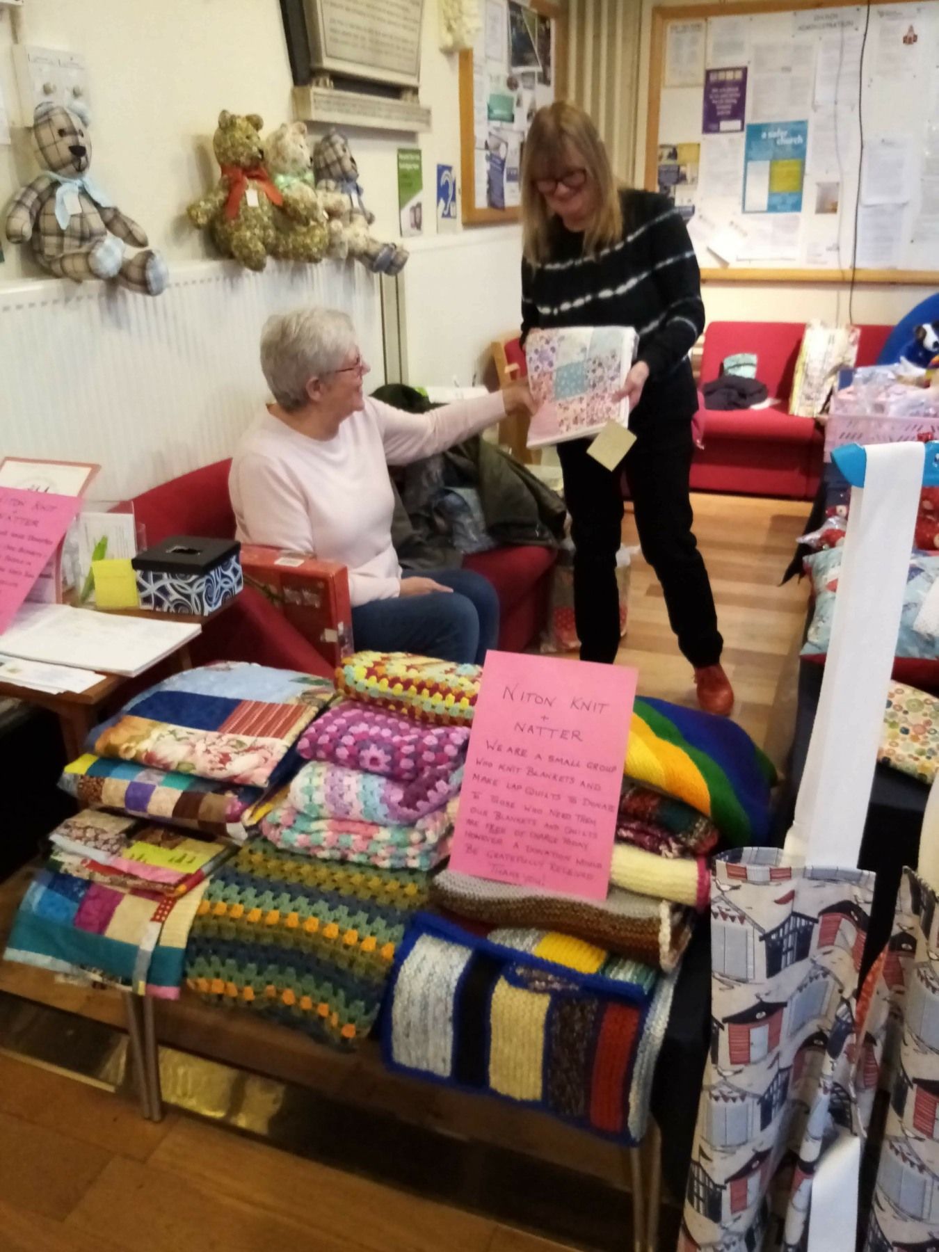 Two women are standing in a room with lots of blankets