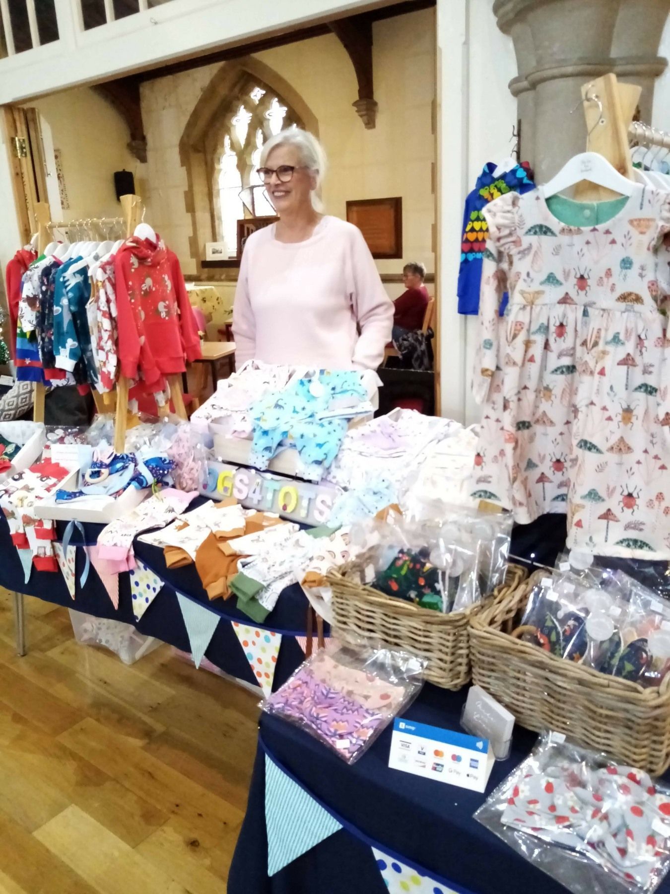 A woman is standing in front of a table with clothes on it.