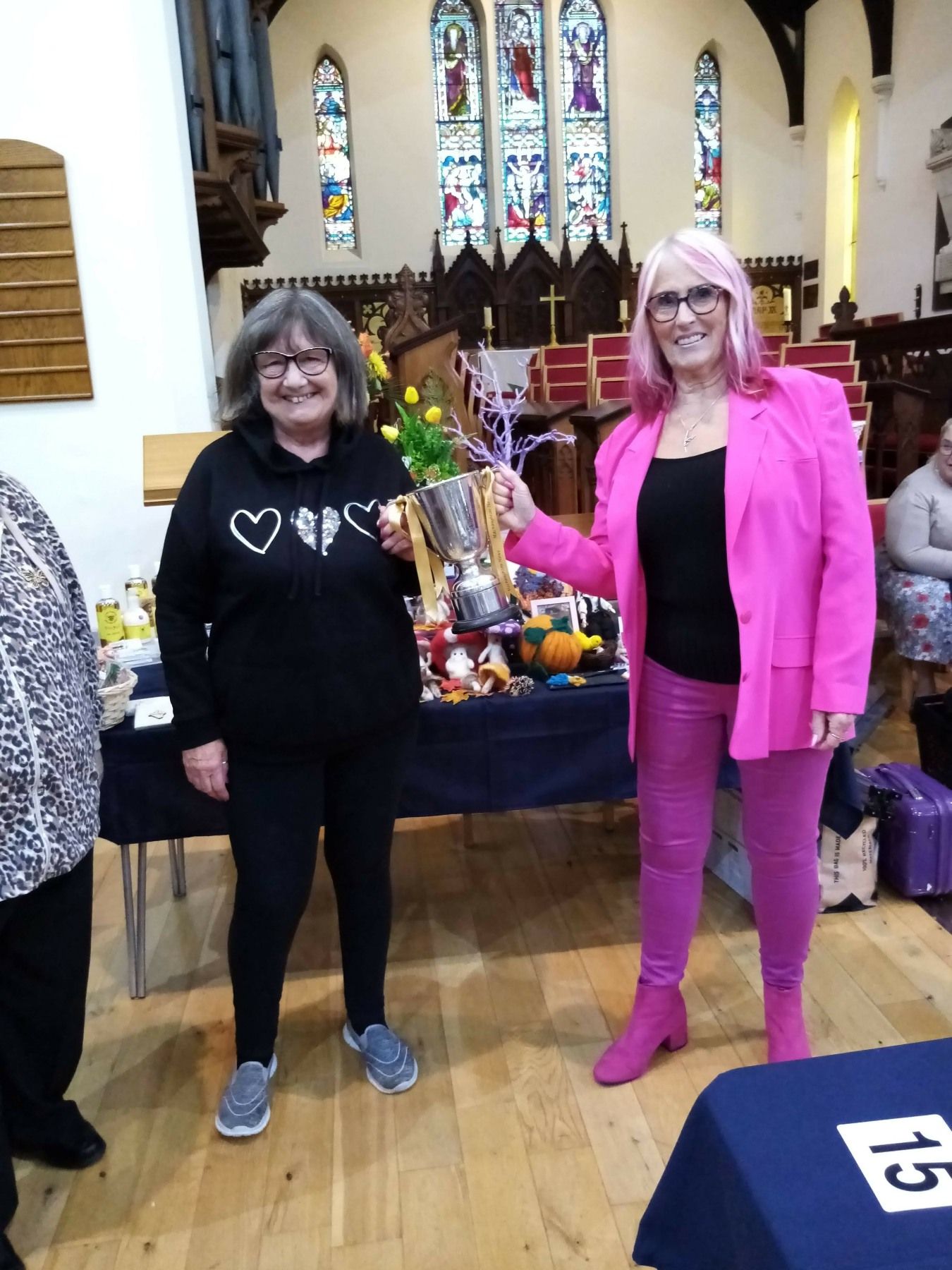 Two women are standing next to each other in a church holding a trophy.