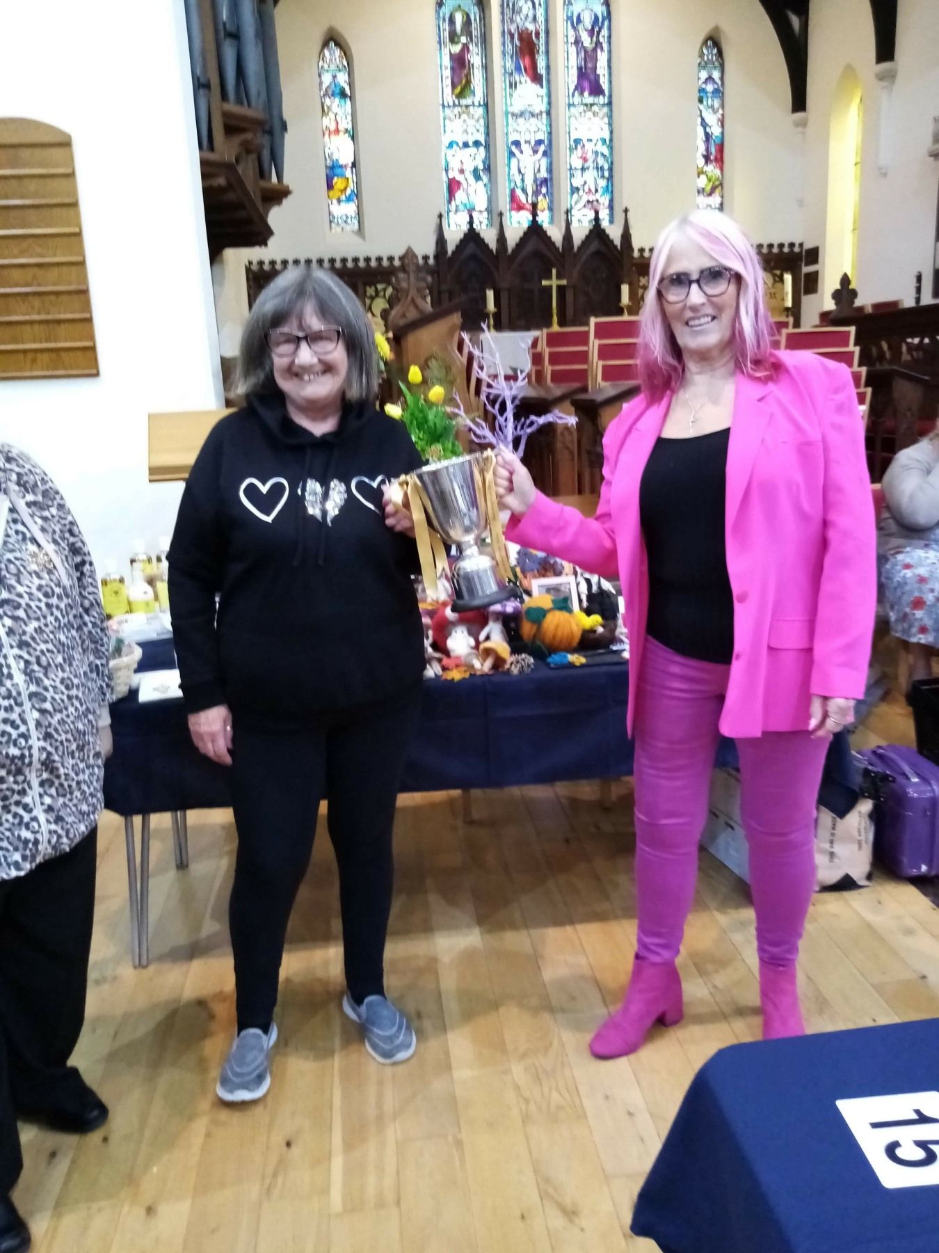 A woman in a pink jacket is holding a trophy