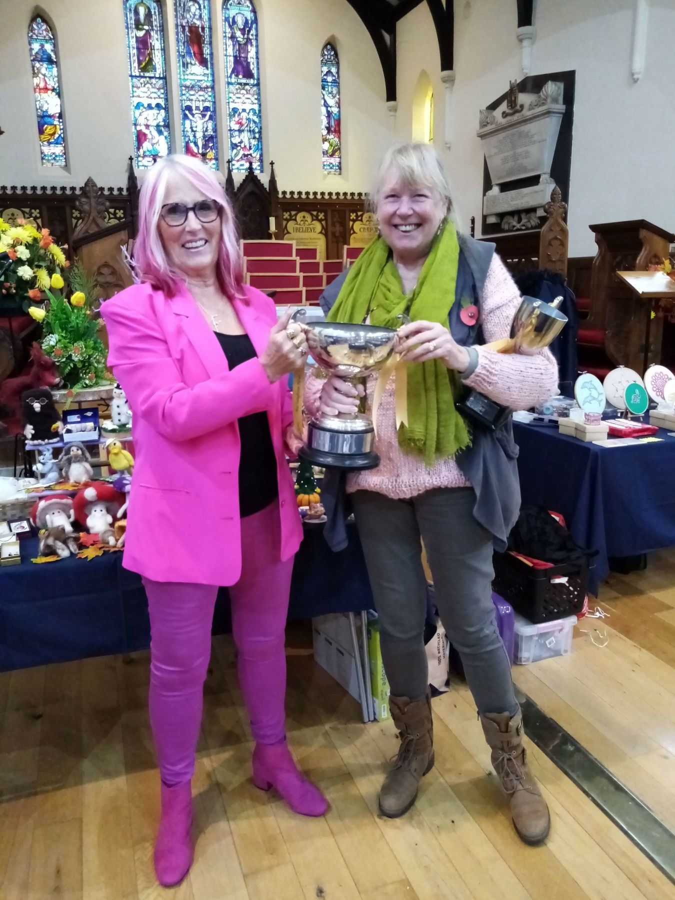 Two women are holding a trophy in a church