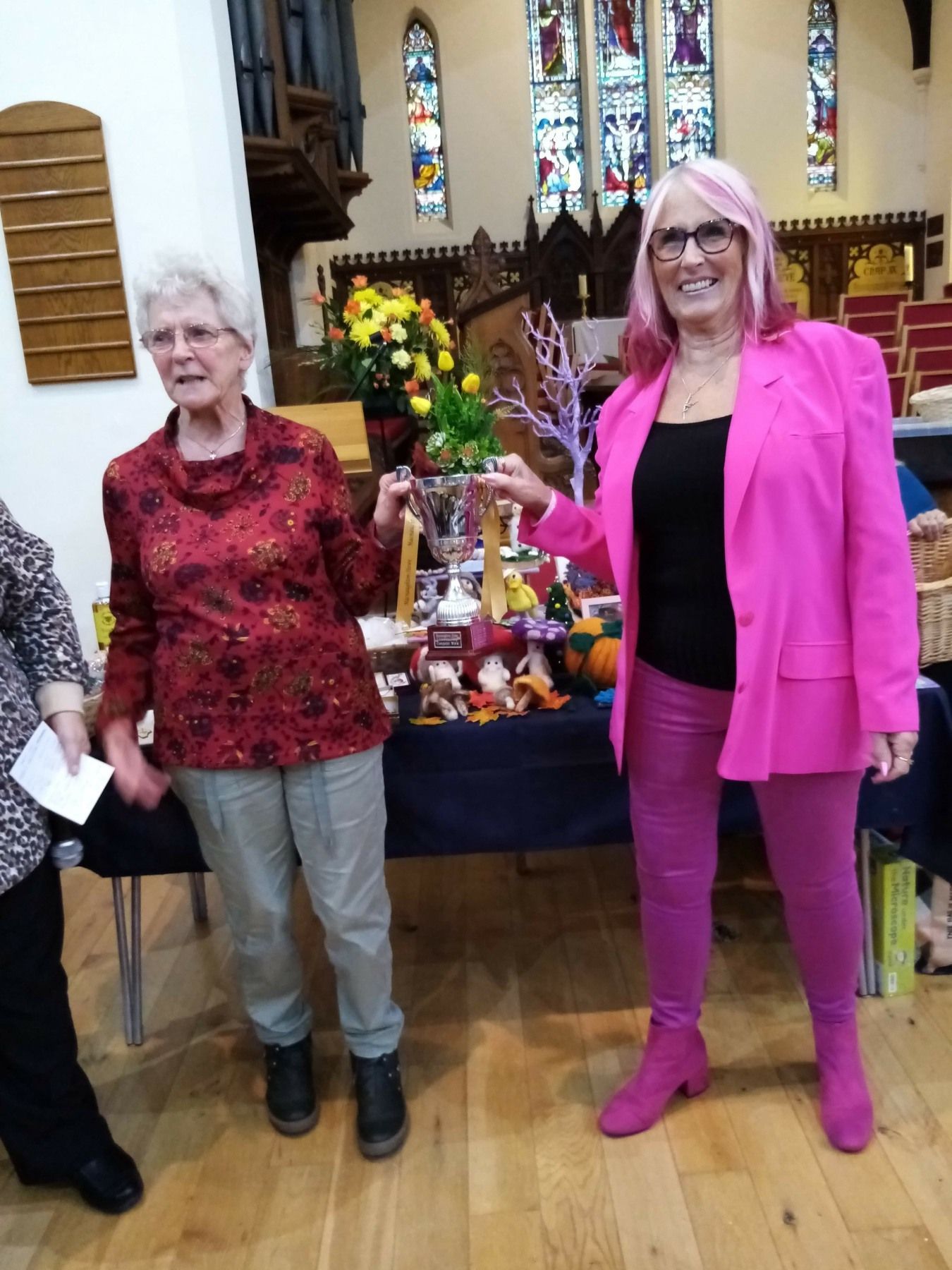 A woman in a pink jacket is standing next to another woman in a church.
