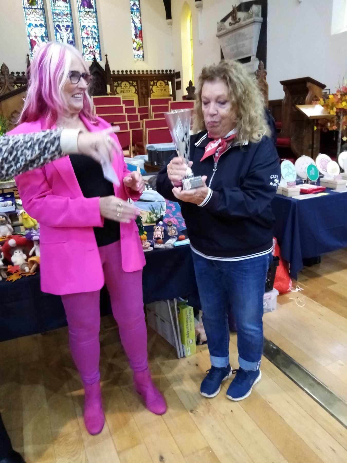 A woman with pink hair is standing next to another woman