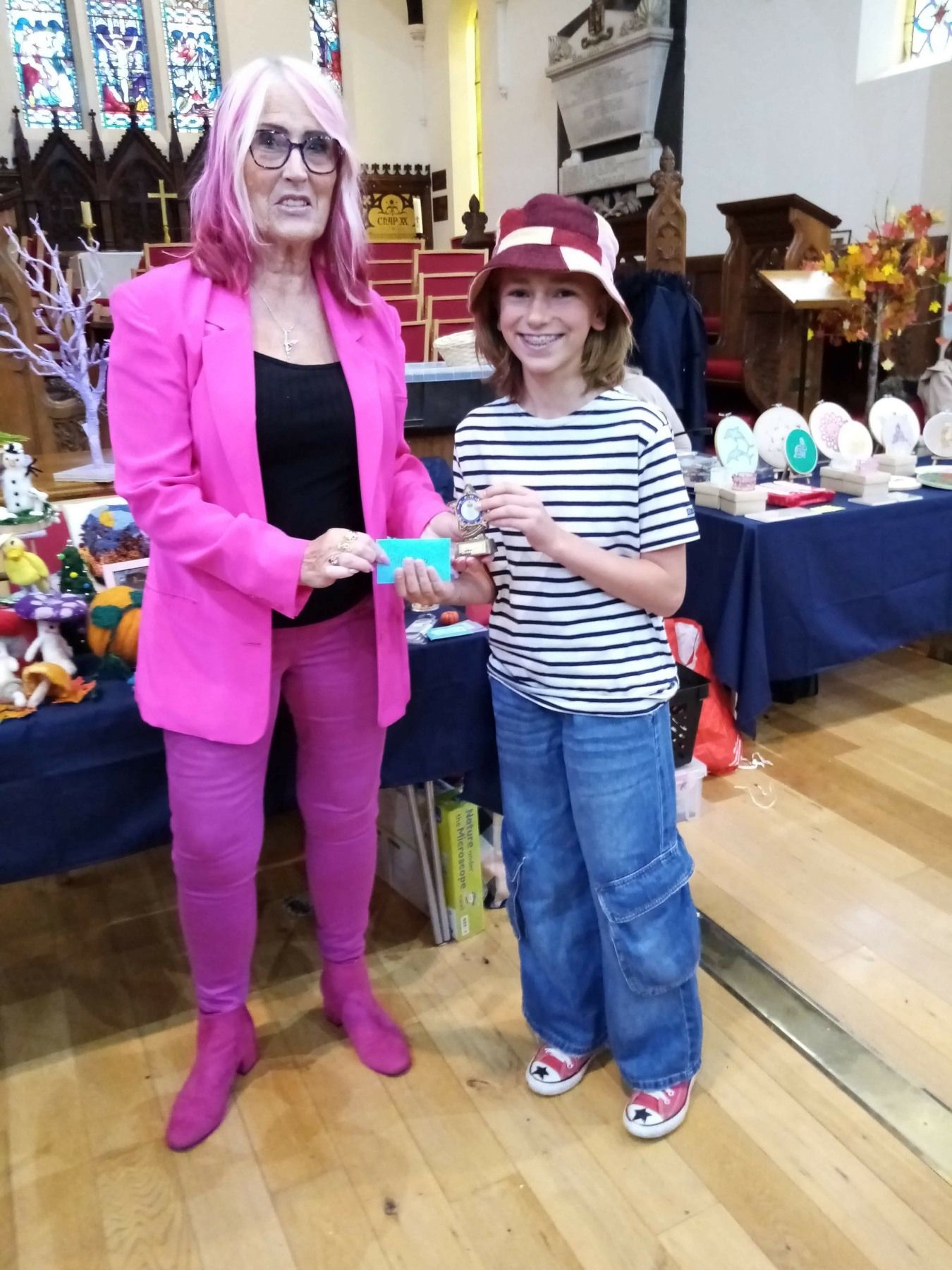 A woman in a pink jacket is standing next to a girl in a striped shirt.