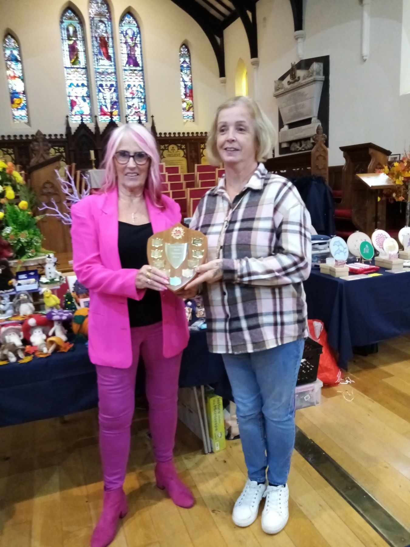 Two women are standing next to each other in a church holding a plaque.