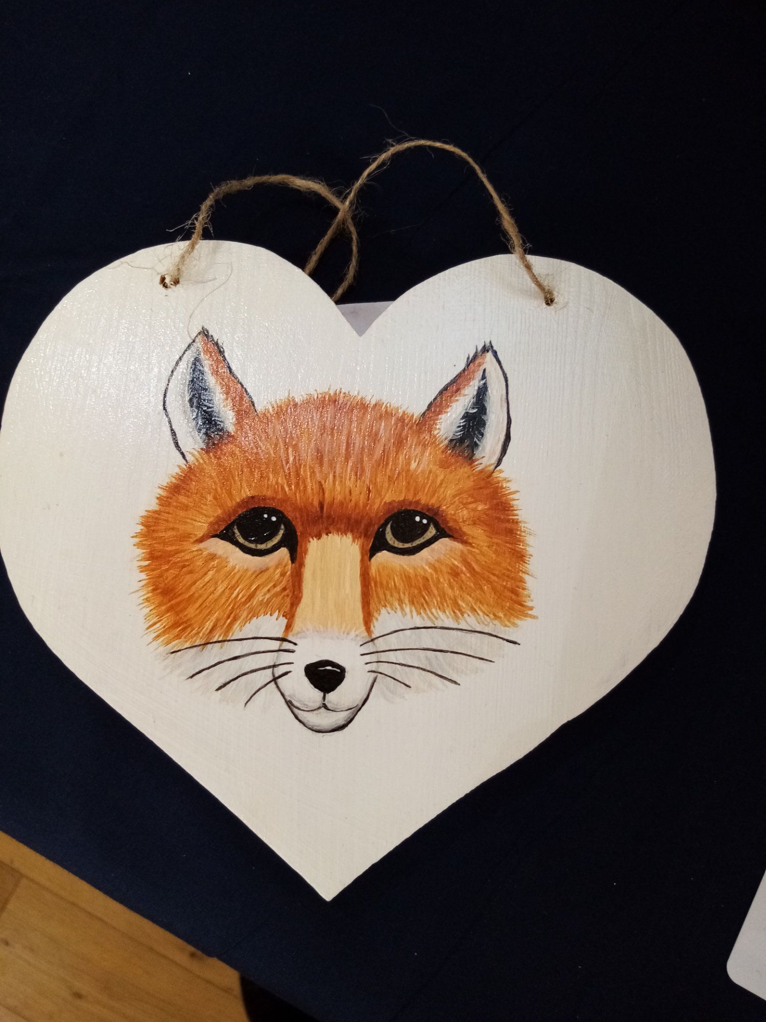 A heart shaped sign with a fox 's face painted on it