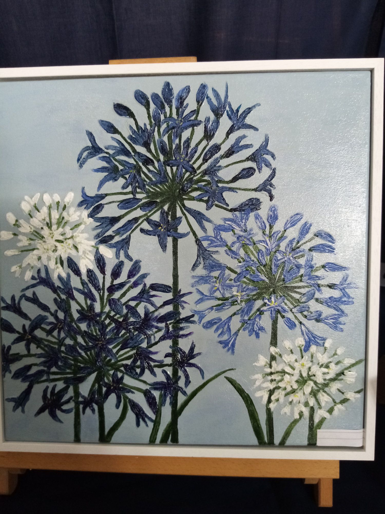A painting of blue and white flowers on an easel