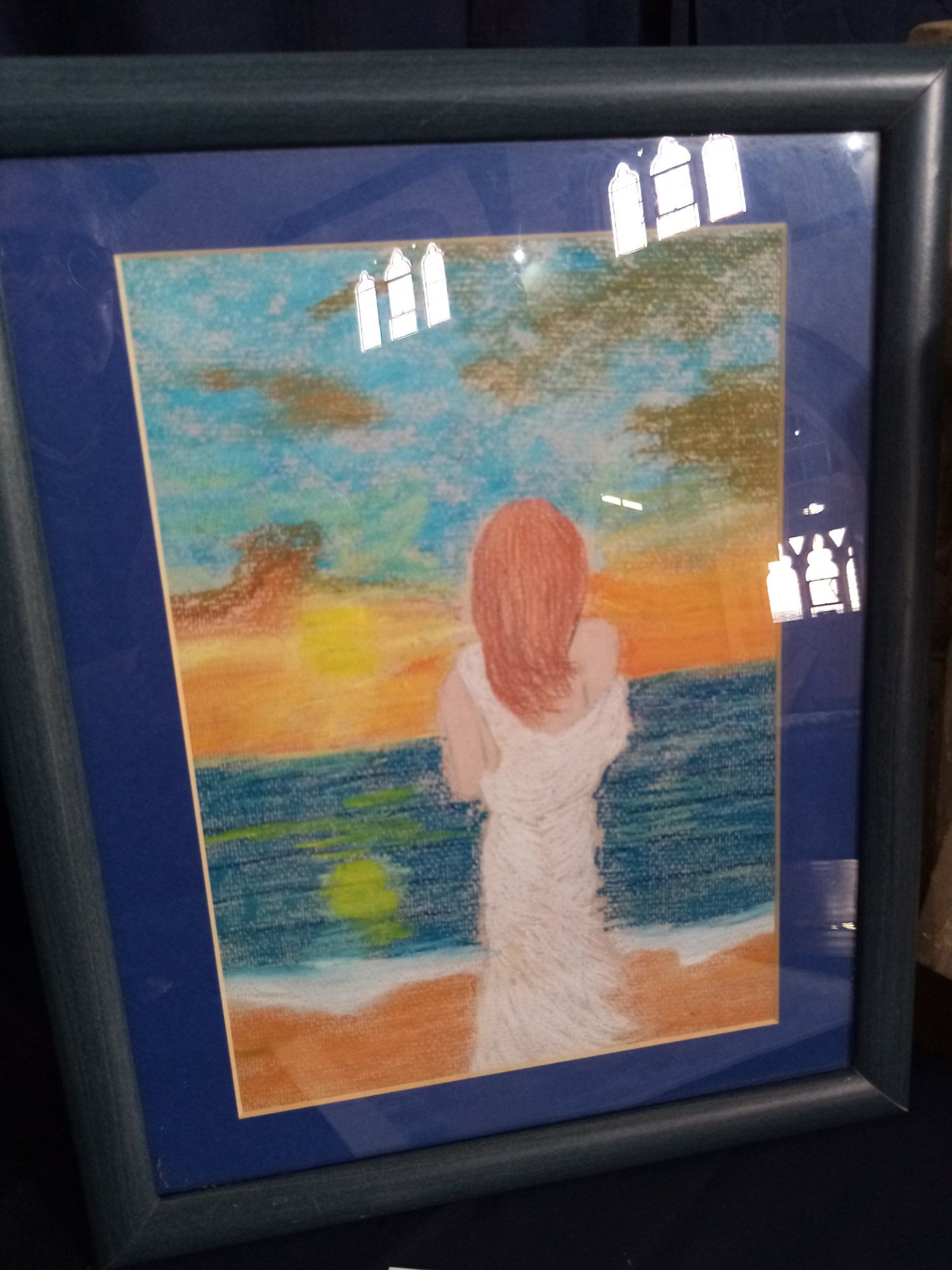 A framed painting of a woman standing on a beach