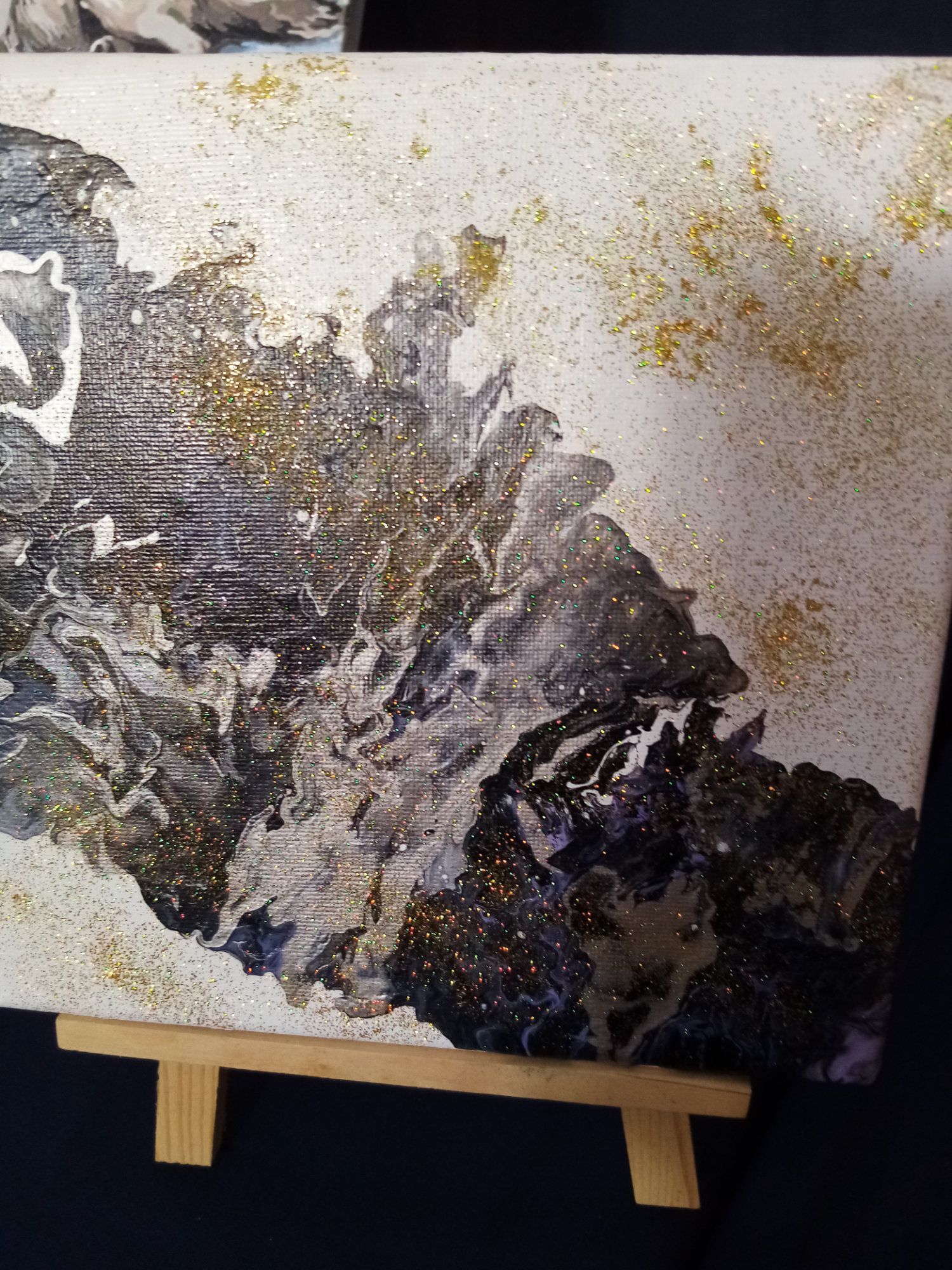 A painting is sitting on a wooden easel.