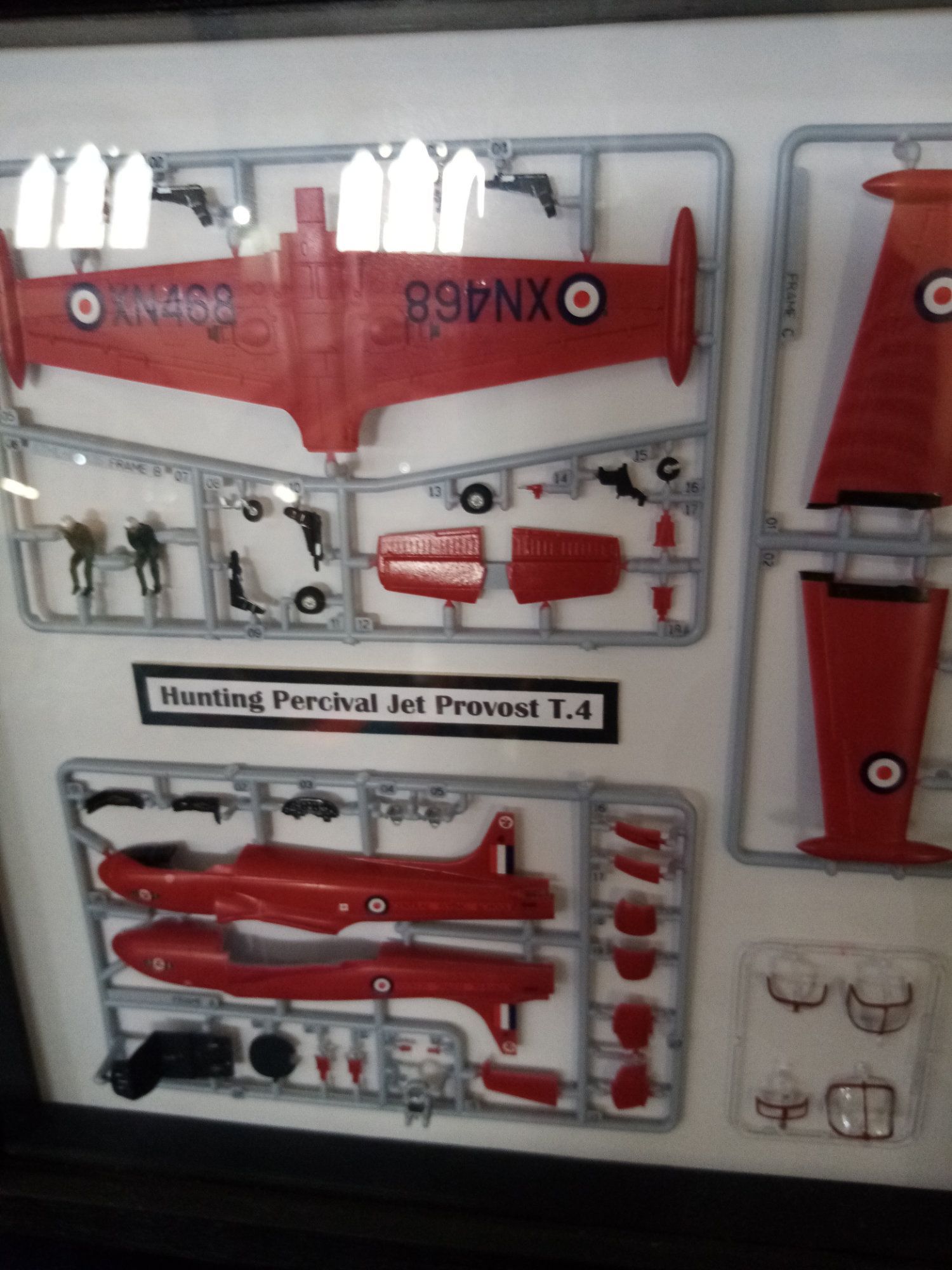 A framed model of a red plane with oxn468 on the tail