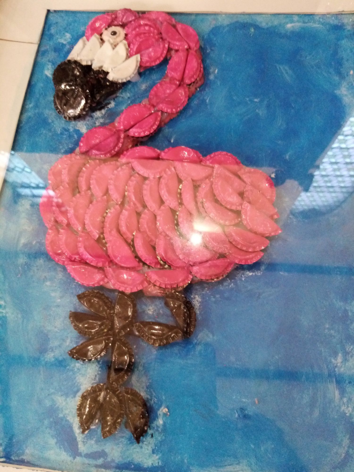 A pink flamingo made out of cupcakes on a blue surface.