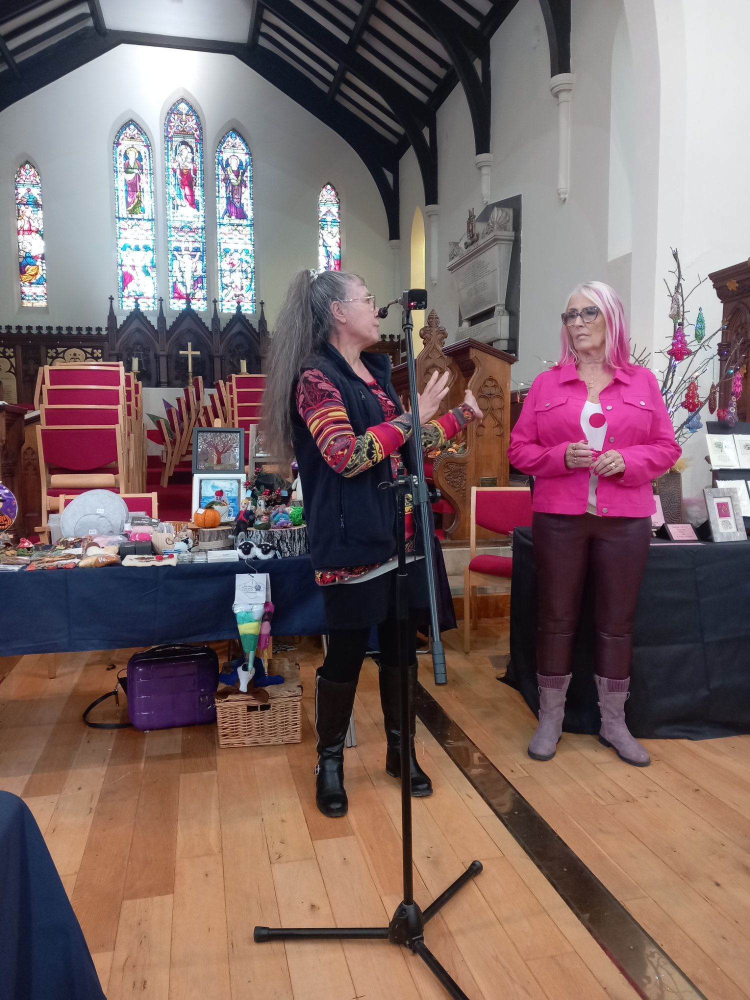 A woman in a pink shirt is standing in front of a microphone in a church.