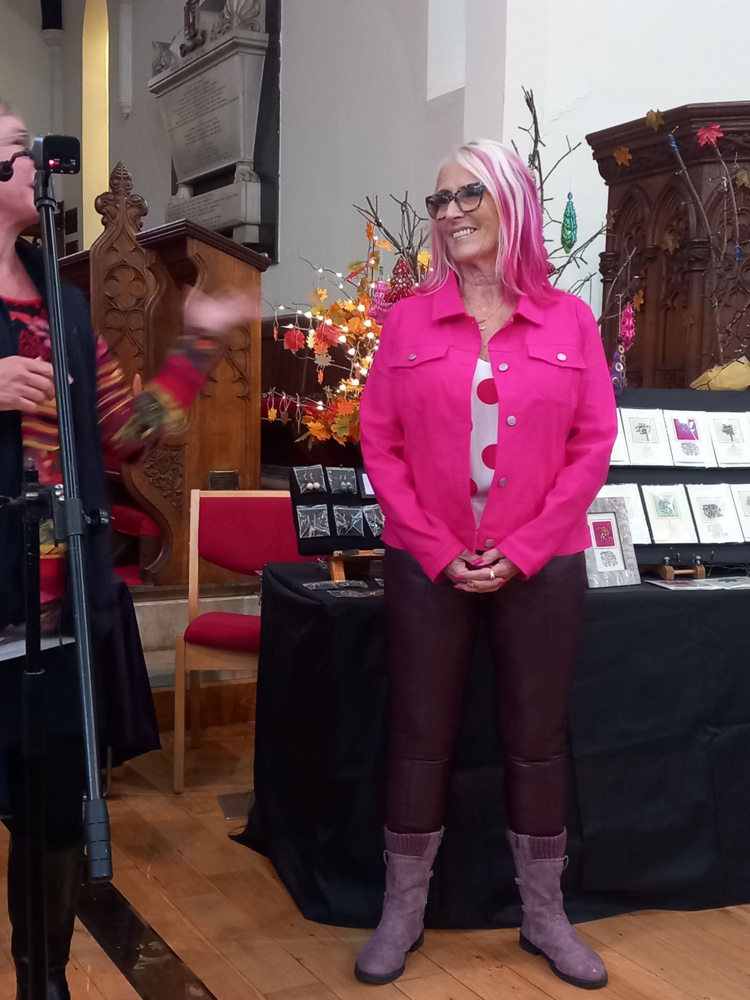 A woman with pink hair is standing in front of a microphone