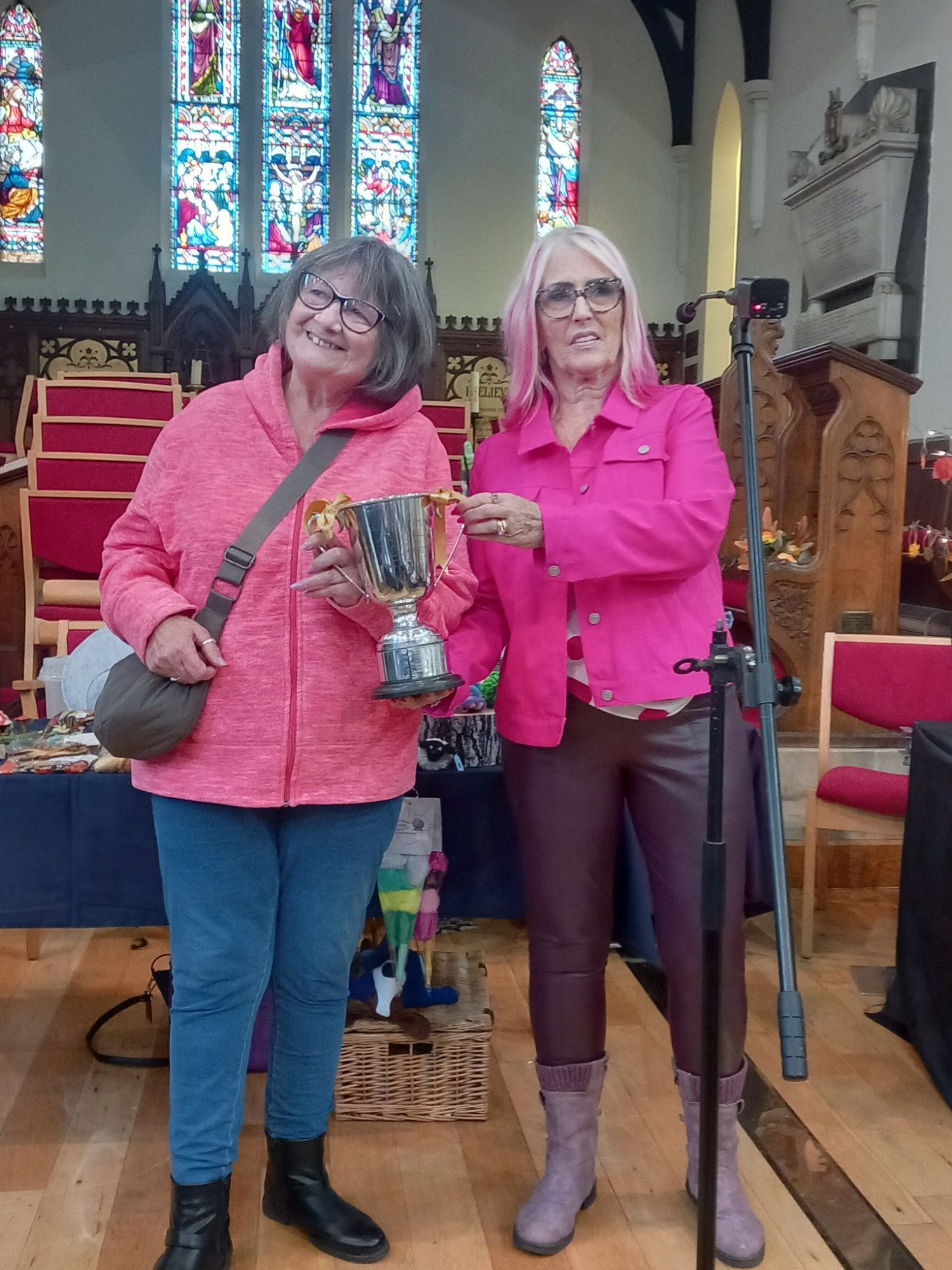 Two women are standing next to each other in a church holding a trophy.