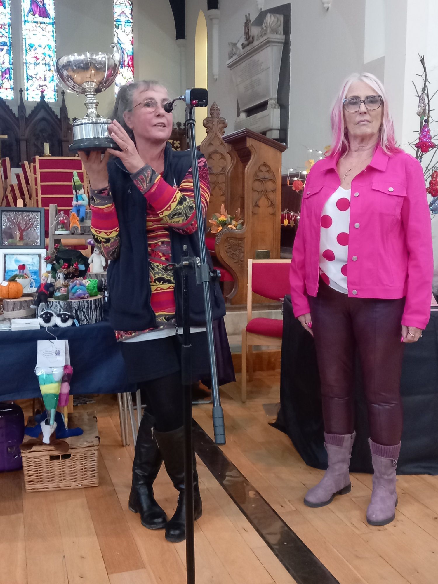 Two women are standing in front of a microphone in a church.