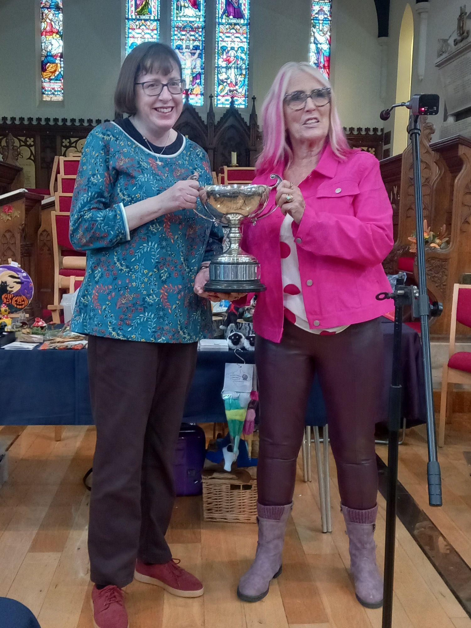 Two women are standing next to each other in a church holding a trophy.