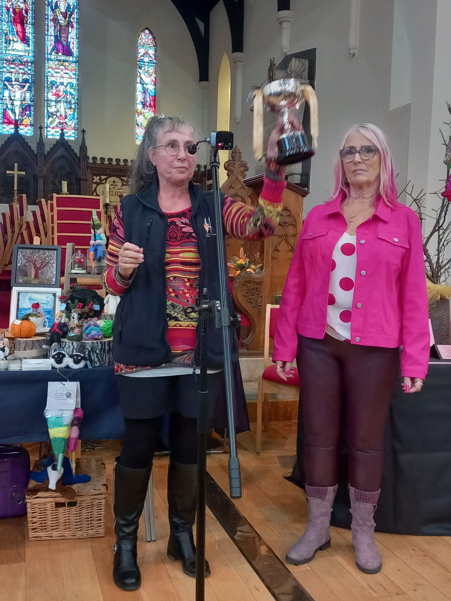 Two women are standing in front of a microphone in a church.