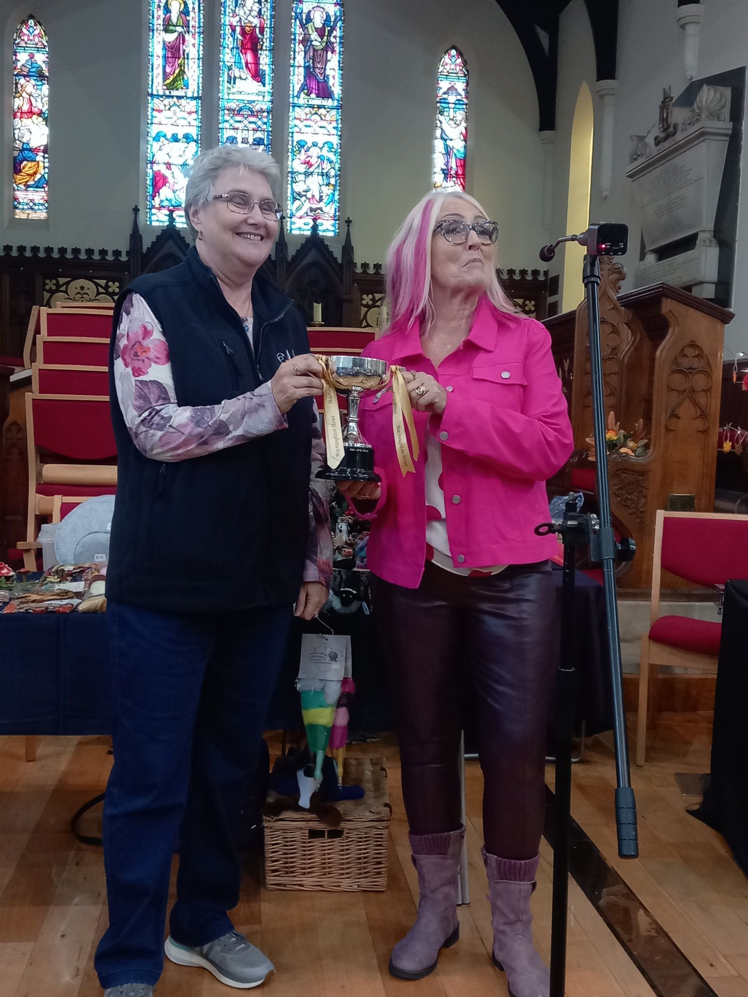 Two women standing in front of a microphone in a church